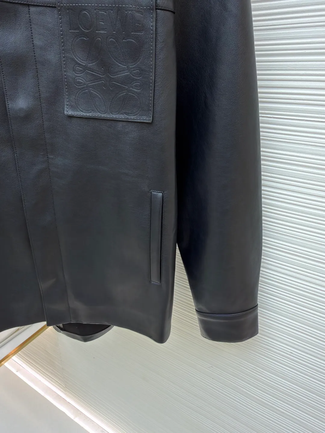 Loewe Anagram pocket zipper leather jacket ●Original version: 38900 purchase and development ●Item number: 1682094-C75 ●Fabric: sheepskin fabric ●Technology: air pump machine embossed production ●Color: black ●Version: fitted version ●Weight: about 1010 grams ●Size: 46-48-50-52 ●Description: Customized ebony pebbled vegetable tanned sheepskin, soft and tough texture, natural texture Presented in matte matte black, the grainy texture reflects subtle light and dark layers under light and shadow, giving static black a dynamic vitality. The iconic Loewe Anagram logo is embellished on the chest patch pocket. It is low-key and powerful. Every inch exudes a low-key and charming luxury luster. Hidden in the public, visible in the wise, it interprets the true connotation of high-end fashion with its versatile appearance. Air pump machine embossed embossing. Through the synergy between precise air pressure control and temperature, the logo pattern is imprinted on the leather surface in a three-dimensional embossed form without damage. Finally, the leather fibers are quickly solidified through a sudden drop in temperature, and the strands are fixed by manual glue. Physical reinforcement technology to fix the seams of the cut pieces through precise point gluing. Manual gluing operation. A wavy glue line is formed along the warp and weft of the cut piece, and the artificial oil edge requires the application of four layers of oil edge agent. Each layer is cooled to a specific temperature and then polished to ensure that the edge is as hard as ceramics and has a uniform gloss. The workmanship is cumbersome and the timeliness is slow. The overall wiring is straight and delicate, the fabric is comfortable and soft, and the color is consistent without color difference. It can be matched with the same style to create a fashionable look and control various occasions. Customized accessories, complete with three standards, same style for men and women!