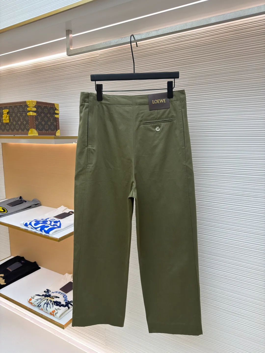 Loewe military green belt trousers ●Original version: purchased and developed by 7161 ●Item number: 1681217-B15 ●Fabric: high weight dyed cotton satin fabric ●Technology: leather patch production ●Color: military green ●Version: loose fit ●Weight: about 530 grams ●Size: 46-48-50-52 ●Description: Made of high-weight cotton satin fabric, high-weight high-temperature dyed cotton satin fabric is a high-end material with excellent texture and functionality. The core of its technology lies in the selection of high-count, long-staple cotton, and the satin weave method to minimize the interweaving points of warp and weft yarns, thereby forming a unique surface that is smooth, supple and with a faint luster. The high weight ensures that the fabric has a tight structure, is crisp and stylish, and has excellent drape and wear resistance. , "Using high-temperature and high-pressure dyeing technology in the dyeing process, the dye molecules can deeply penetrate into the core of the fiber, thereby achieving high color saturation, strong color fastness and not easy to fade. This process not only gives the fabric a rich and lasting color, but also makes it plump and soft to the touch. It also retains the natural breathability of cotton fiber, achieving a both luxurious and practical wearing experience. The contrasting color decorative belt echoes the theme of military uniforms and allows for flexible waist adjustment; the back is embossed with bronzing leather patches, which use high temperature and high pressure. The brand logo is permanently embossed on the leather and sewn onto the back of the jacket. This process makes the pattern clear and durable, becoming a low-key and powerful symbol of the brand's identity. The style adopts a regular fit and a mid-rise straight design to ensure clean lines and comfortable wearing. The front gathers are an important decorative element and provide room for movement in the functional legs. The pocket design is both practical and simple, while the rear button-stuck welt pocket enhances the sophistication of workwear style.