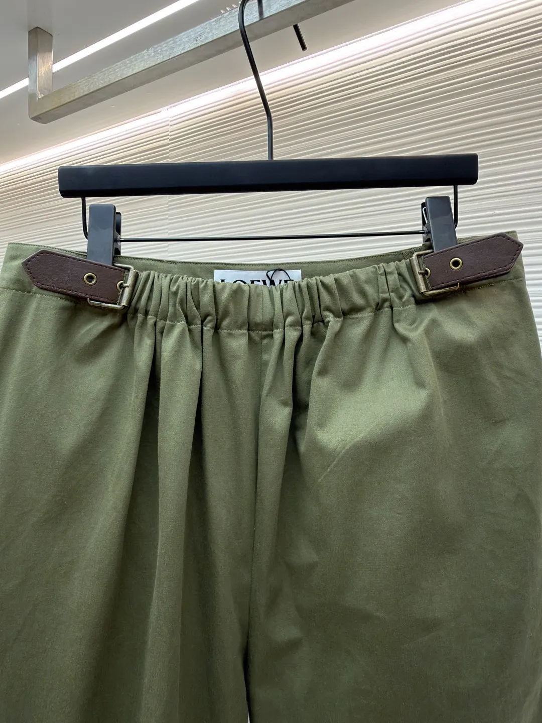 Loewe military green belt trousers ●Original version: purchased and developed by 7161 ●Item number: 1681217-B15 ●Fabric: high weight dyed cotton satin fabric ●Technology: leather patch production ●Color: military green ●Version: loose fit ●Weight: about 530 grams ●Size: 46-48-50-52 ●Description: Made of high-weight cotton satin fabric, high-weight high-temperature dyed cotton satin fabric is a high-end material with excellent texture and functionality. The core of its technology lies in the selection of high-count, long-staple cotton, and the satin weave method to minimize the interweaving points of warp and weft yarns, thereby forming a unique surface that is smooth, supple and with a faint luster. The high weight ensures that the fabric has a tight structure, is crisp and stylish, and has excellent drape and wear resistance. , "Using high-temperature and high-pressure dyeing technology in the dyeing process, the dye molecules can deeply penetrate into the core of the fiber, thereby achieving high color saturation, strong color fastness and not easy to fade. This process not only gives the fabric a rich and lasting color, but also makes it plump and soft to the touch. It also retains the natural breathability of cotton fiber, achieving a both luxurious and practical wearing experience. The contrasting color decorative belt echoes the theme of military uniforms and allows for flexible waist adjustment; the back is embossed with bronzing leather patches, which use high temperature and high pressure. The brand logo is permanently embossed on the leather and sewn onto the back of the jacket. This process makes the pattern clear and durable, becoming a low-key and powerful symbol of the brand's identity. The style adopts a regular fit and a mid-rise straight design to ensure clean lines and comfortable wearing. The front gathers are an important decorative element and provide room for movement in the functional legs. The pocket design is both practical and simple, while the rear button-stuck welt pocket enhances the sophistication of workwear style.