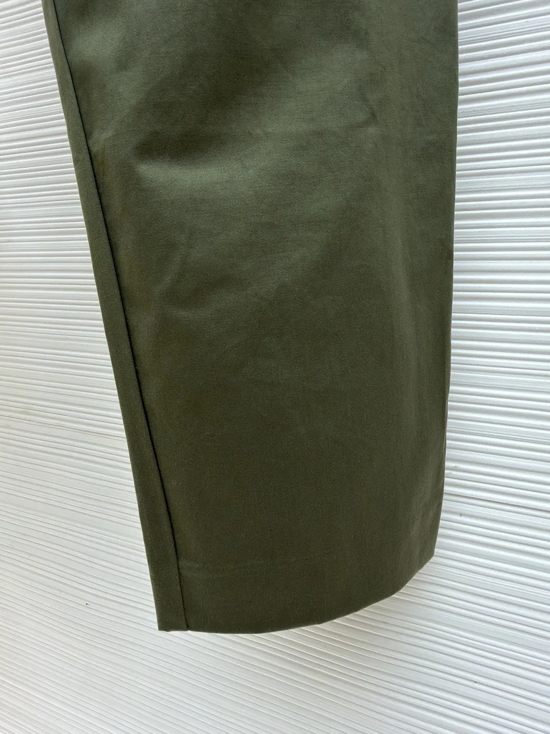 Loewe military green belt trousers ●Original version: purchased and developed by 7161 ●Item number: 1681217-B15 ●Fabric: high weight dyed cotton satin fabric ●Technology: leather patch production ●Color: military green ●Version: loose fit ●Weight: about 530 grams ●Size: 46-48-50-52 ●Description: Made of high-weight cotton satin fabric, high-weight high-temperature dyed cotton satin fabric is a high-end material with excellent texture and functionality. The core of its technology lies in the selection of high-count, long-staple cotton, and the satin weave method to minimize the interweaving points of warp and weft yarns, thereby forming a unique surface that is smooth, supple and with a faint luster. The high weight ensures that the fabric has a tight structure, is crisp and stylish, and has excellent drape and wear resistance. , "Using high-temperature and high-pressure dyeing technology in the dyeing process, the dye molecules can deeply penetrate into the core of the fiber, thereby achieving high color saturation, strong color fastness and not easy to fade. This process not only gives the fabric a rich and lasting color, but also makes it plump and soft to the touch. It also retains the natural breathability of cotton fiber, achieving a both luxurious and practical wearing experience. The contrasting color decorative belt echoes the theme of military uniforms and allows for flexible waist adjustment; the back is embossed with bronzing leather patches, which use high temperature and high pressure. The brand logo is permanently embossed on the leather and sewn onto the back of the jacket. This process makes the pattern clear and durable, becoming a low-key and powerful symbol of the brand's identity. The style adopts a regular fit and a mid-rise straight design to ensure clean lines and comfortable wearing. The front gathers are an important decorative element and provide room for movement in the functional legs. The pocket design is both practical and simple, while the rear button-stuck welt pocket enhances the sophistication of workwear style.