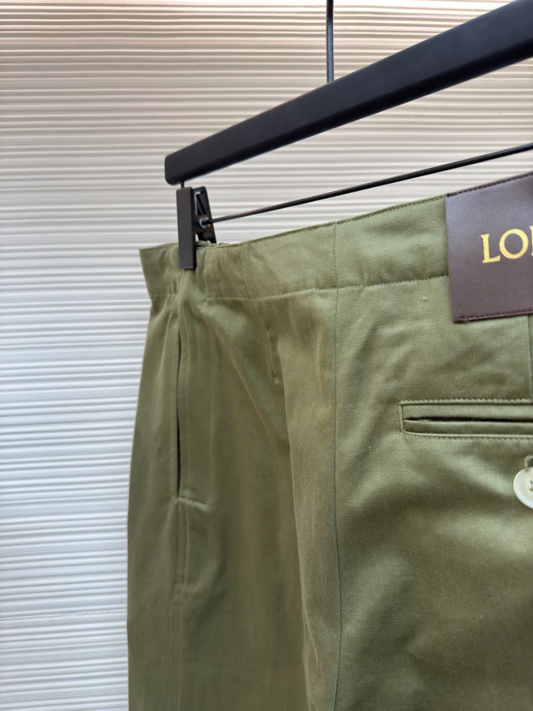 Loewe military green belt trousers ●Original version: purchased and developed by 7161 ●Item number: 1681217-B15 ●Fabric: high weight dyed cotton satin fabric ●Technology: leather patch production ●Color: military green ●Version: loose fit ●Weight: about 530 grams ●Size: 46-48-50-52 ●Description: Made of high-weight cotton satin fabric, high-weight high-temperature dyed cotton satin fabric is a high-end material with excellent texture and functionality. The core of its technology lies in the selection of high-count, long-staple cotton, and the satin weave method to minimize the interweaving points of warp and weft yarns, thereby forming a unique surface that is smooth, supple and with a faint luster. The high weight ensures that the fabric has a tight structure, is crisp and stylish, and has excellent drape and wear resistance. , "Using high-temperature and high-pressure dyeing technology in the dyeing process, the dye molecules can deeply penetrate into the core of the fiber, thereby achieving high color saturation, strong color fastness and not easy to fade. This process not only gives the fabric a rich and lasting color, but also makes it plump and soft to the touch. It also retains the natural breathability of cotton fiber, achieving a both luxurious and practical wearing experience. The contrasting color decorative belt echoes the theme of military uniforms and allows for flexible waist adjustment; the back is embossed with bronzing leather patches, which use high temperature and high pressure. The brand logo is permanently embossed on the leather and sewn onto the back of the jacket. This process makes the pattern clear and durable, becoming a low-key and powerful symbol of the brand's identity. The style adopts a regular fit and a mid-rise straight design to ensure clean lines and comfortable wearing. The front gathers are an important decorative element and provide room for movement in the functional legs. The pocket design is both practical and simple, while the rear button-stuck welt pocket enhances the sophistication of workwear style.