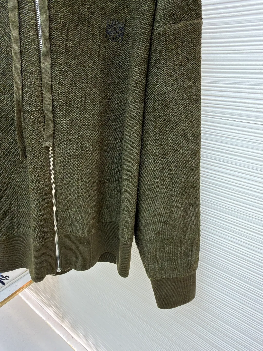 Loewe embroidered hooded zipper cardigan ●Original version: Purchased and developed by 9856 ●Item number: 1682194-B70 ●Material: wool blended fabric ●Technology: embroidery production ●Color: khaki green ●Version: Loose fit ●Weight: about 935 grams ●Size: S-M-L-XL ●Description: Selected high-quality wool as the main body, with unique terry cloth stitching technology, is a highlight of this sweatshirt. This stitching method not only gives the sweatshirt a unique texture and texture, but also demonstrates our stringent quality requirements in every detail. Every seam is tight and even, like a carefully carved work of art, which not only enhances the durability of the clothing, but also adds a unique fashion charm. Ribbed cuffs and hem are the perfect combination of classic and practical. They fit the body well, prevent cold wind from getting in, and provide excellent warmth. At the same time, the elastic properties of the ribs also ensure the comfort of wearing it and will not cause any restrictions on body movements. On the chest, the high-precision calculation system of the computer embroidery machine controls the coordinated operation of the machine head, needle bar, and thread spool. The fabric frame moves accurately in the horizontal and vertical directions to form a stitch track. The upper and lower thread tensions are adjusted to ensure that the stitches are smooth and free of floating threads, forming anagram embroidery with an error of ±0.1mm. The overall wiring is straight and delicate, the fabric is comfortable and soft, and the color is consistent without color difference. It can be matched with the same style to create a fashionable look and control various occasions. Customized accessories, complete with three standards, same style for men and women!