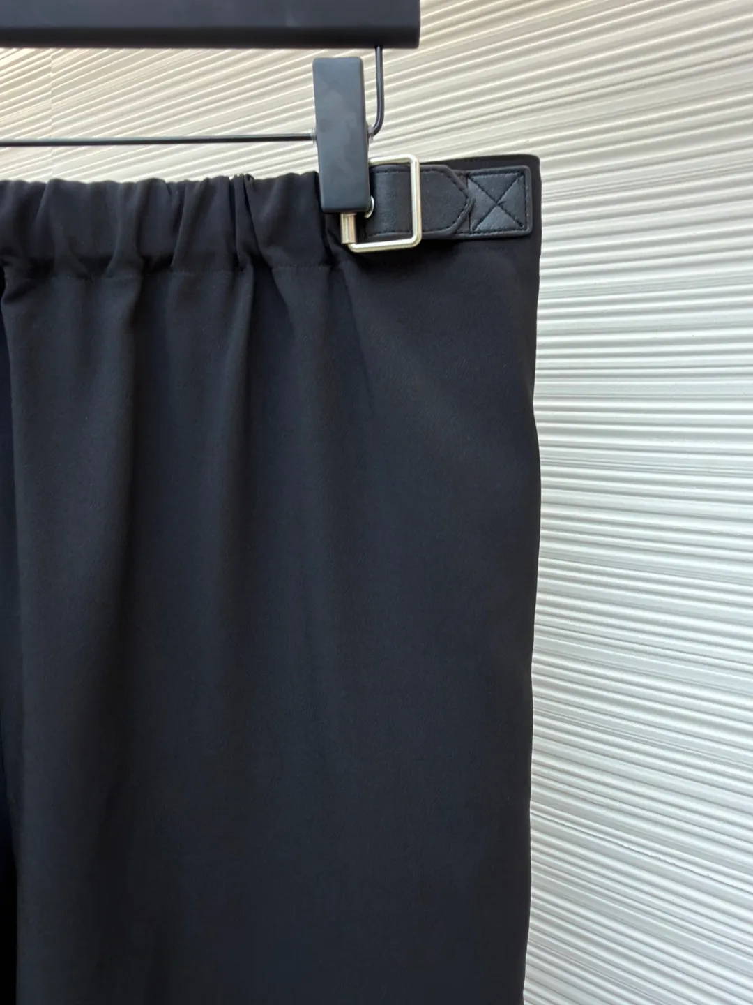 Loewe black belt trousers ●Original version: purchased and developed for 12900 ●Item number: 1682112-B15 ●Fabric: high weight dyed cotton satin fabric ●Technology: leather patch production ●Color: black ●Version: loose fit ●Weight: about 580 grams ●Size: 46-48-50-52 ●Description: Made of high-weight cotton satin fabric, high-weight high-temperature dyed cotton satin fabric is a high-end material with excellent texture and functionality. The core of its technology lies in the selection of high-count, long-staple cotton, and the satin weave method to minimize the interweaving points of warp and weft yarns, thereby forming a unique surface that is smooth, supple and with a faint luster. The high weight ensures that the fabric has a tight structure, is crisp and stylish, and has excellent drape and wear resistance. , "Using high-temperature and high-pressure dyeing technology in the dyeing process, the dye molecules can deeply penetrate into the core of the fiber, thereby achieving high color saturation, strong color fastness and not easy to fade. This process not only gives the fabric a rich and lasting color, but also makes it plump and soft to the touch. It also retains the natural breathability of cotton fiber, achieving a both luxurious and practical wearing experience. The contrasting color decorative belt echoes the theme of military uniforms and allows for flexible waist adjustment; the back is embossed with bronzing leather patches, which use high temperature and high pressure. The brand logo is permanently embossed on the leather and sewn onto the back of the jacket. This process makes the pattern clear and durable, becoming a low-key and powerful symbol of the brand's identity. The style adopts a regular fit and a mid-rise straight design to ensure clean lines and comfortable wearing. The front gathers are an important decorative element and provide room for movement in the functional legs. The pocket design is both practical and simple, while the rear button-stuck welt pocket enhances the sophistication of workwear style.