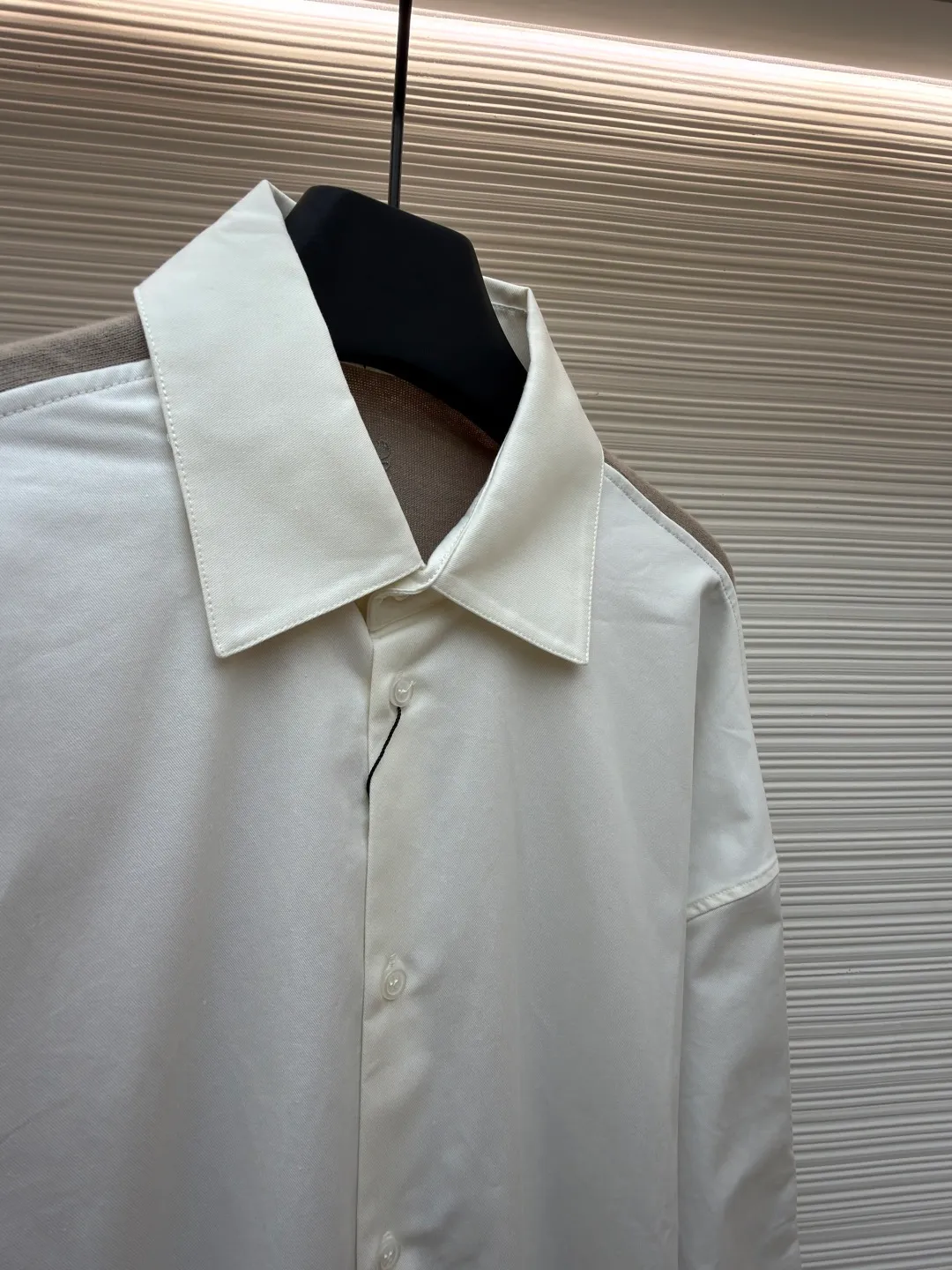 LOEWE cotton and knitted spliced shirt ●Original version: purchased and developed by 12479 ●Item number: 1680887-B50 ●Fabric: high-count cotton yarn fabric ●Technology: mechanical embroidery production ●Version: fitted version ●Weight: about 350 grams ●Size: 36-38-40-42 ●Description: The front panel is made of high-count cotton yarn through a weaving process with high warp density and low weft density to make a light and thin fabric with excellent breathability. The surface is smooth and flat, and feels as smooth as silk. At the same time, it retains the natural skin-friendly properties of cotton, making it snug and comfortable without any strange feeling. Because the warp yarns are closely arranged, the surface of the fabric shows longitudinal texture and soft luster, enhancing the visual sense of luxury. The back panel is woven with extremely fine wool yarn through high-count spinning technology to make a fabric with moderate density. It feels soft and skin-friendly, and has a delicate velvet feel on the surface. Wool fiber has a natural hollow structure, which can lock in still air and form an excellent thermal insulation layer. Even if it is light and thin, it has a good thermal insulation effect. Under the back collar, the high-precision calculation system of the computerized embroidery machine controls the coordinated operation of the machine head, needle bar, and thread spool. The fabric frame moves accurately in the horizontal and vertical directions to form a stitch track. The upper and lower thread tensions are adjusted to ensure that the stitches are smooth and free of floating threads, forming anagram embroidery with an error of ±0.1mm. The overall wiring is straight and delicate, the fabric is comfortable and soft, and the color is consistent without color difference. It can be matched with the same style to create a fashionable look and control various occasions. Customized accessories, complete with three standards, same style for men and women!