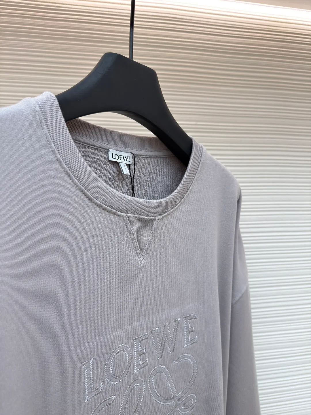 Loewe zigzag thread appliqué round neck sweatshirt ●Original version: Purchased and developed by 3621 ●Item number: 1680966-A90 ●Fabric: Fleece fabric ●Technology: Laser cutting appliqué production ●Version: Fitted version ●Weight: about 580g ●Size: 2*2 thread, 470g. The fish scale bottom fabric forms a fish scale pattern through a specific weaving process, and the plates are arranged and interwoven according to the warp and weft patterns and shapes to ensure clear texture and excellent texture. The fabric has been carefully produced and processed, and has good durability, lightness, softness, and good breathability. The edge-strengthened branches of the appliqué embroidery add a rough industrial look by imitating zigzag-shaped stitches. The appliqué stitches are in the form of trapezoidal zigzags, resembling interlaced canine teeth; emphasizing high stitch density and sharp turns, like saw blade cutting marks. Trim the seam allowance and cut off excess fabric along the dogtooth stitches to retain the jagged three-dimensional effect. After the garment is made, it is made through frying process. The garment is dyed, washed and aged using new environmentally friendly technology. Fabrics are dyed using a stone grinding method, and the garments are continuously immersed in dye and tumbled. After frying the sand, the fabric fades slightly, changing the color of the original fabric to show a nostalgic color with different shades of light and dark. The neckline adopts a structural feature formed by a V-shaped rib weaving method, which visually has a unique sense of line and extensibility. The rib structure itself has good elasticity and stretchability; inserts are added to the shoulder seams to increase the service life. The neckline, hem, and cuffs are all spliced ​​with double-needle threading. The body and sleeves are structurally split and quilted. The fabric material has high ductility and no sense of restraint. The overall wiring is straight and delicate, the fabric is comfortable and soft, and the color is consistent without color difference. It can be matched with the same style to create a fashionable look and control various occasions. Customized accessories, complete with three standards, same style for men and women!