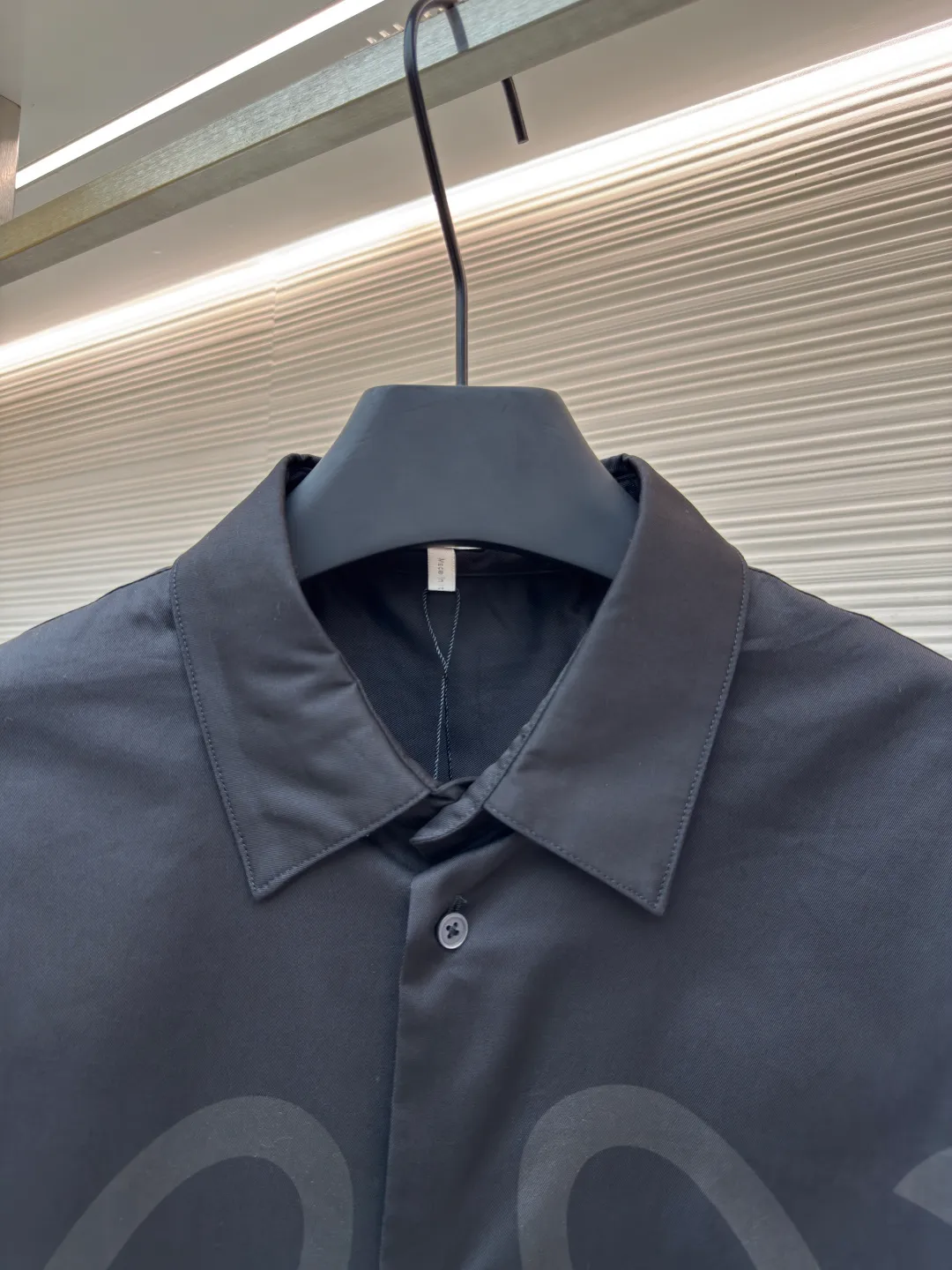 Loewe concealed logo lapel shirt ●Original version: Purchased and developed by 6454 ●Item number: 1680723-A75 ●Fabric: Light cotton poplin shirt fabric ●Technology: Printing ●Version: Fitted version ●Weight: about 290 grams ●Size: 36-38-40-42 ●Description: Poplin is a classic cotton fabric characterized by a large density difference between warp and weft yarns, forming a fine diamond-shaped grainy texture. This structure not only gives the fabric a refreshing and breathable wearing feel, but also ensures that its texture is light and thin but has a crisp texture, avoiding the shortcomings of ordinary thin cotton that easily collapses, perfectly supporting the neat silhouette of the shirt, while maintaining the unique skin-friendly comfort of cotton. The chest is decorated with a discharge printing process; discharge printing is a special process that erodes through the dyed base fabric to reveal the light-colored pattern of the original fabric. This makes the Anagram logo not simply covered on the fabric, but integrated with the fabric, feeling smooth and traceless, showing a low-key and high-end matte effect. Fit and design The shirt adopts a loose fit of standard length; it is precisely tailored to the pattern. It is neither too loose nor deliberately slim, aiming to create a clean silhouette and is extremely tolerant to all body types. The standard length ensures that the hem can be tucked into trousers or hang naturally, meeting a variety of wear needs, including formal and casual. The overall wiring is straight and delicate, the fabric is comfortable and soft, and the color is consistent without color difference. It can be matched with the same style to create a fashionable look and control various occasions. Customized accessories, complete with three standards, same style for men and women!