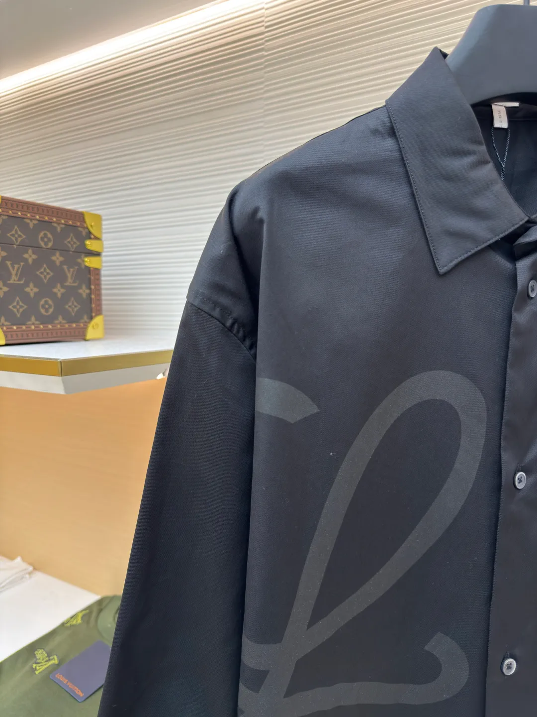 Loewe concealed logo lapel shirt ●Original version: Purchased and developed by 6454 ●Item number: 1680723-A75 ●Fabric: Light cotton poplin shirt fabric ●Technology: Printing ●Version: Fitted version ●Weight: about 290 grams ●Size: 36-38-40-42 ●Description: Poplin is a classic cotton fabric characterized by a large density difference between warp and weft yarns, forming a fine diamond-shaped grainy texture. This structure not only gives the fabric a refreshing and breathable wearing feel, but also ensures that its texture is light and thin but has a crisp texture, avoiding the shortcomings of ordinary thin cotton that easily collapses, perfectly supporting the neat silhouette of the shirt, while maintaining the unique skin-friendly comfort of cotton. The chest is decorated with a discharge printing process; discharge printing is a special process that erodes through the dyed base fabric to reveal the light-colored pattern of the original fabric. This makes the Anagram logo not simply covered on the fabric, but integrated with the fabric, feeling smooth and traceless, showing a low-key and high-end matte effect. Fit and design The shirt adopts a loose fit of standard length; it is precisely tailored to the pattern. It is neither too loose nor deliberately slim, aiming to create a clean silhouette and is extremely tolerant to all body types. The standard length ensures that the hem can be tucked into trousers or hang naturally, meeting a variety of wear needs, including formal and casual. The overall wiring is straight and delicate, the fabric is comfortable and soft, and the color is consistent without color difference. It can be matched with the same style to create a fashionable look and control various occasions. Customized accessories, complete with three standards, same style for men and women!