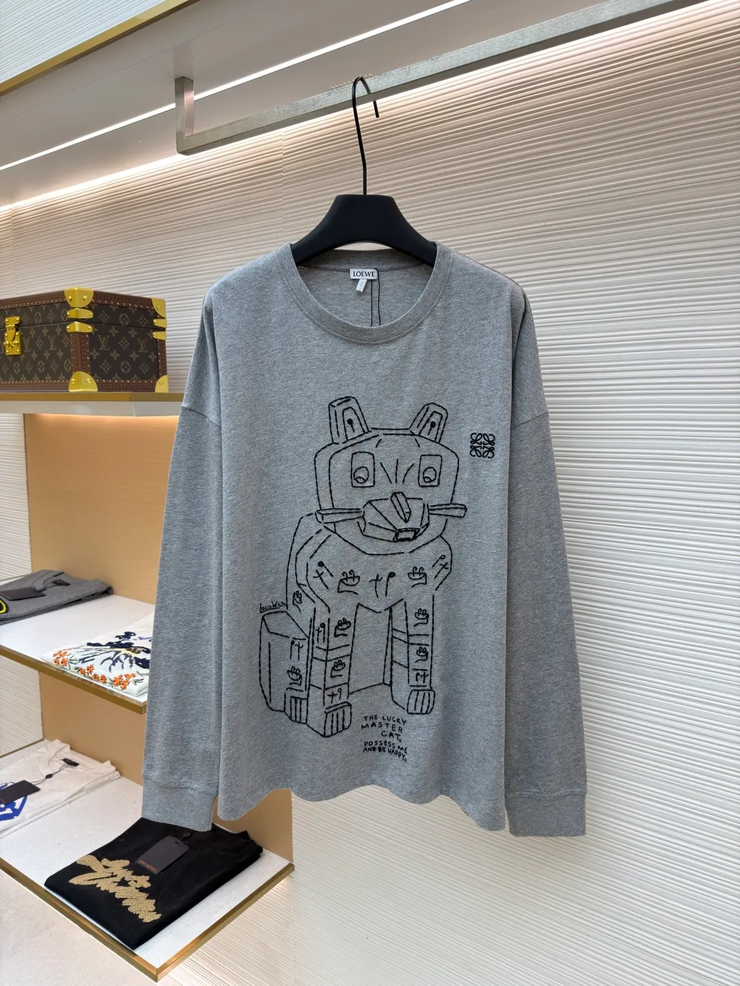 Loewe Stone Cat Round Neck Long Sleeve ●Original version: Purchased and developed by 5148 ●Item number: 1681939-A15 ●Fabric: Cotton jersey fabric ●Technology: Rice grain line embroidery production ●Color: gray ●Version: Fitted version ●Weight: about 250 grams ●Size: High-count combed cotton yarn eliminates most of the short hairiness through compact spinning process, making the yarn smoother and stronger. The woven fabric structure is extremely dense, flat and soft, with excellent anti-pilling ability and durability, while retaining the natural advantages of pure cotton, which is breathable and skin-friendly. The neckline is made of 32S 1x1 rib with a weight of 300g. The finer yarn count creates a more delicate and tight thread, which provides better resilience and anti-deformation than ordinary ribs, ensuring that the neckline can still remain stiff after being put on and taken off many times. The rice grain line embroidery process uses special ultra-fine embroidery thread and high-density stitching to create a pattern outline as delicate and continuous as grains. Its core feature lies in the precise arrangement of ultra-fine stitches, which require 12-15 stitches per centimeter to form full lines, and the edges present a handmade micro-waving effect. The fabric achieves a stroke-like gradient of thickness and flow. The overall pattern is light, breathable and smooth to the touch. It looks like a line outline from a distance, but the texture of interwoven fibers can be seen up close. It is especially suitable for expressing delicate details such as logo outlines and geometric borders. Anagram embroidery: Using three-dimensional embroidery technology, the logo clearly restores the spacing curve. The mercerized embroidery thread with luster is selected, combined with complex embroidery needlework and fine detail processing to create a three-dimensional relief embroidery effect. Classic trademark letter design, fine embroidery and dense stitching, clear font and strong sense of lines and three-dimensionality. The overall wiring is straight and delicate, the fabric is comfortable and soft, and the color is consistent without color difference. It can be matched with the same style to create a fashionable look and control various occasions. Customized accessories, complete with three standards, same style for men and women!