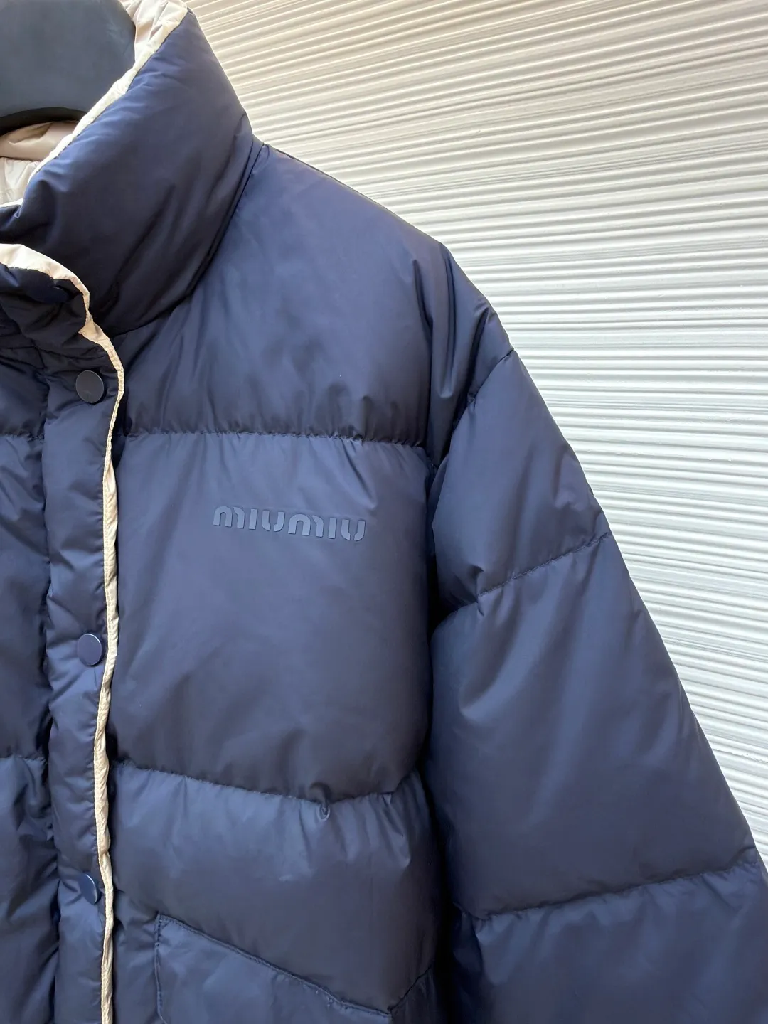 MIUMIU reversible stand collar down jacket ●Original version: purchased and developed by 21060 ●Item number: 1681385-D05 ●Fabric: white duck down fabric ●Technology: mechanical down filling ●Color: navy/khaki ●Version: fitted version ●Weight: about 675 grams ●Size: 36-38-40-42 ●Description: The filling is white duck down with 90% down content, which is one of the gold standards of down quality. "90% down content" means that the down content is extremely high and there are very few impurities such as feather stalks. The down tufts can capture more air and form an efficient thermal insulation layer, thus providing several times the loft and warmth of ordinary down while being lighter in weight. In the double-sided structure, ensuring that the down is evenly distributed between the two layers of fabric without clumping is the core challenge of the down filling process. The stand-up collar design not only improves the neatness of the shape, but also enhances the windproof and warm performance of the neck. Its internal structure needs to be stiff enough to maintain a three-dimensional shape, while at the same time ensuring the comfort of contact with the skin. The precision stitching in conjunction with the overall design not only plays a role in fixing the down and preventing displacement, but the uniformity, tension and pattern of the stitches have become important decorative elements, reflecting rigorous industrial aesthetics. The overall wiring is straight and delicate, the fabric is comfortable and soft, and the color is consistent without color difference. It can be matched with the same style to create a fashionable look and control various occasions. Customized accessories, complete with three standards, same style for men and women!