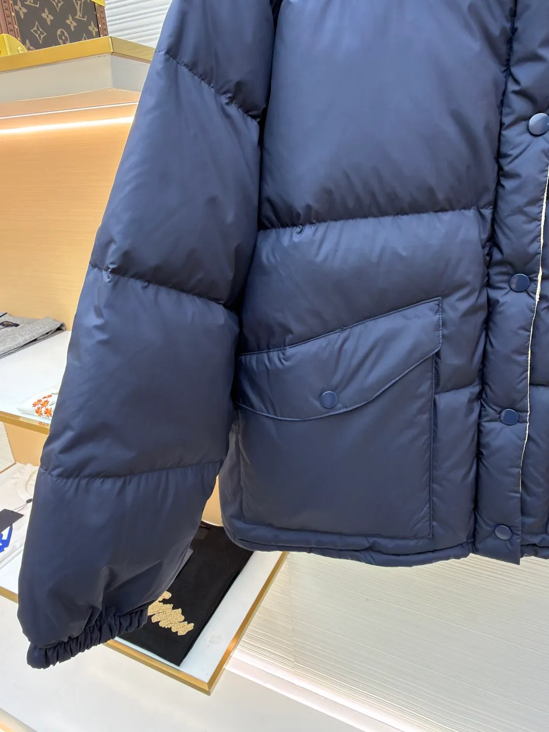 MIUMIU reversible stand collar down jacket ●Original version: purchased and developed by 21060 ●Item number: 1681385-D05 ●Fabric: white duck down fabric ●Technology: mechanical down filling ●Color: navy/khaki ●Version: fitted version ●Weight: about 675 grams ●Size: 36-38-40-42 ●Description: The filling is white duck down with 90% down content, which is one of the gold standards of down quality. "90% down content" means that the down content is extremely high and there are very few impurities such as feather stalks. The down tufts can capture more air and form an efficient thermal insulation layer, thus providing several times the loft and warmth of ordinary down while being lighter in weight. In the double-sided structure, ensuring that the down is evenly distributed between the two layers of fabric without clumping is the core challenge of the down filling process. The stand-up collar design not only improves the neatness of the shape, but also enhances the windproof and warm performance of the neck. Its internal structure needs to be stiff enough to maintain a three-dimensional shape, while at the same time ensuring the comfort of contact with the skin. The precision stitching in conjunction with the overall design not only plays a role in fixing the down and preventing displacement, but the uniformity, tension and pattern of the stitches have become important decorative elements, reflecting rigorous industrial aesthetics. The overall wiring is straight and delicate, the fabric is comfortable and soft, and the color is consistent without color difference. It can be matched with the same style to create a fashionable look and control various occasions. Customized accessories, complete with three standards, same style for men and women!