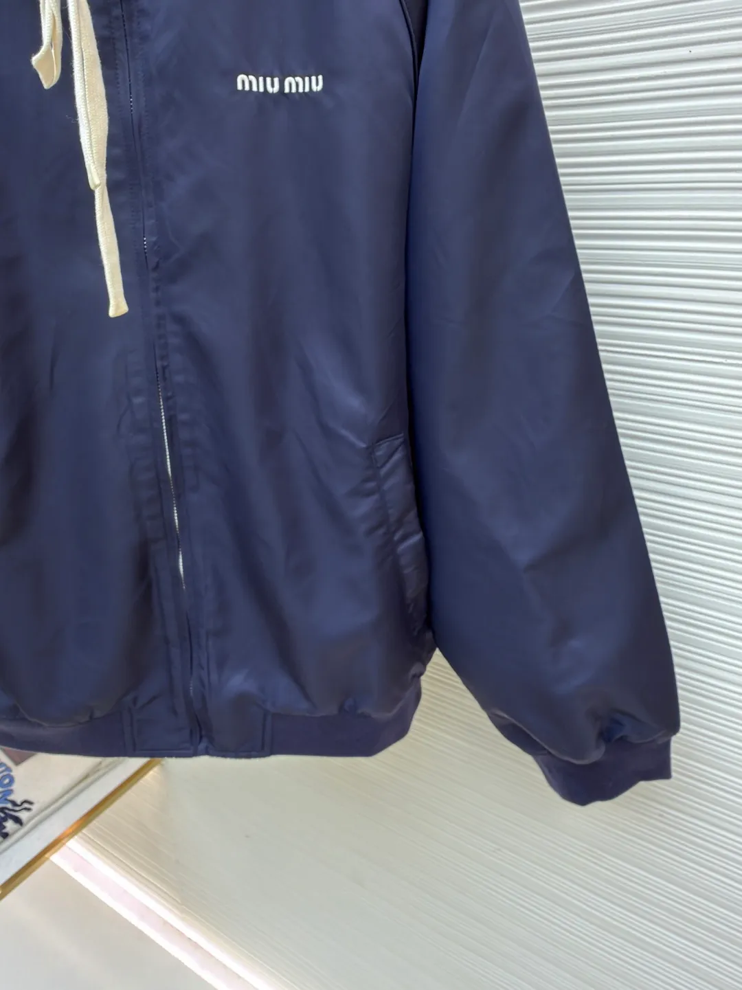 MIUMIU reversible technical fabric and fleece jacket ●Original version: 28200 purchase and development ●Item number: 1682256-C00 ●Fabric: wool blended anti-static plush fabric ●Technology: high temperature pre-shrunk production ●Color: blue/grey ●Version: fitted version ●Weight: about 890 grams ●Size: 36-38-40-42 ●Description: This Miu The Miu navy jacket is made of high-density polyester fabric, which has been treated with water-repellent treatment. The surface has a fine matte texture and has good windproof performance. The body is cut with raglan sleeves, and the three-dimensional patterning technology is used to make the shoulder lines more ergonomic, and there is no sense of restraint when moving. The neckline is spliced ​​with gray fleece lining, which is reinforced with double-needle hemming technology. The drawstring is made of natural cotton rope and has been brushed. The texture is soft and waxy and not easy to deform. The front is equipped with a customized metal zipper, and the smoothness of the gear rail has been tested multiple times. The zipper puller and brand logo are both made by laser engraving. The ribbed edges on the hem and cuffs are made of spandex blended material and are pre-shrunk to prevent them from loosening after long-term wear. The overall stitching uses dual processes of flat turning and overlocking. The stitching is even and fine, reaching the high standard of 12 stitches per inch, ensuring both a stiff silhouette and durability. The overall wiring is straight and delicate, the fabric is comfortable and soft, and the color is consistent without color difference. It can be matched with the same style to create a fashionable look and control various occasions. Customized accessories, complete with three standards, same style for men and women!