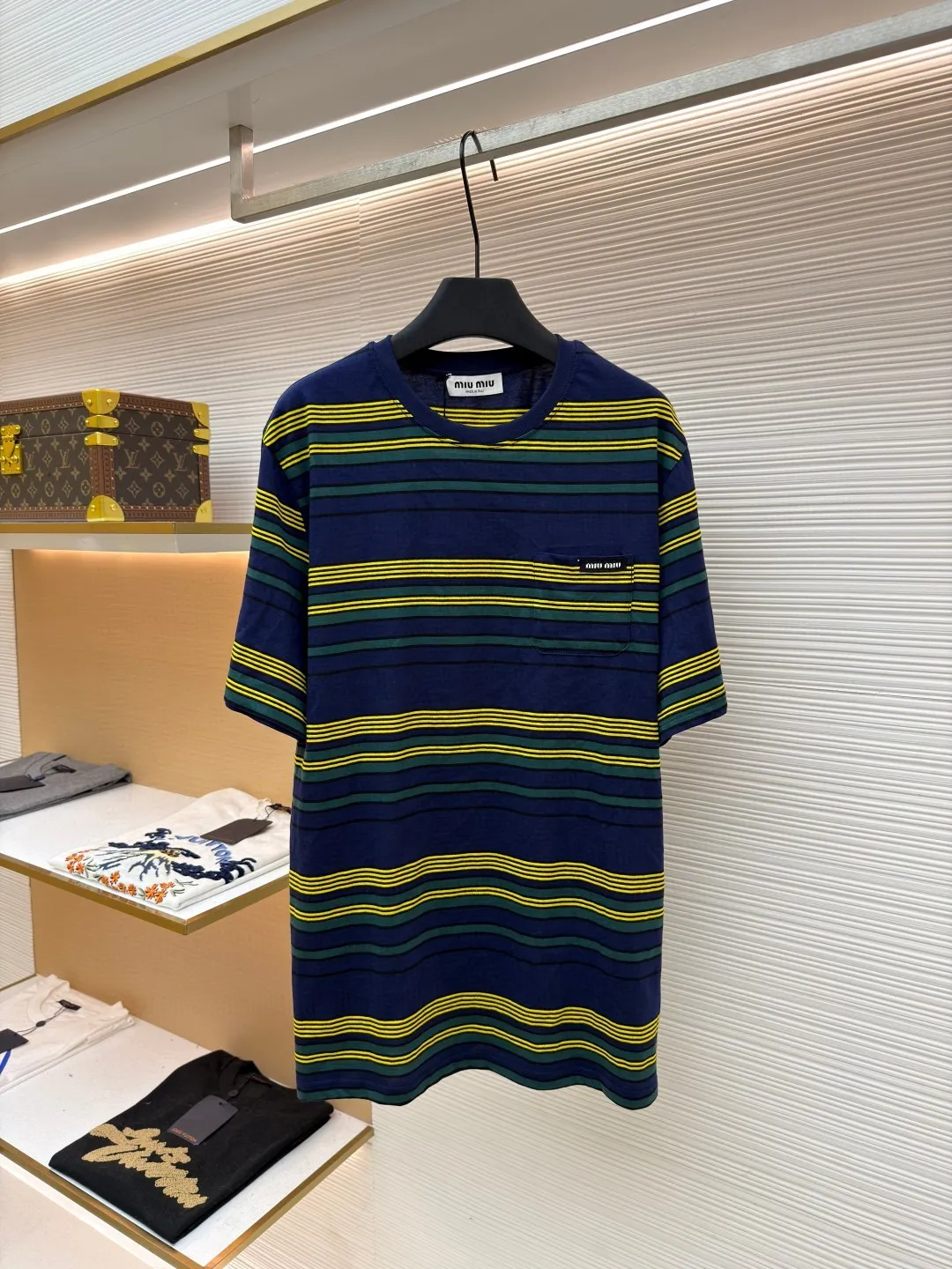 MIUMIU yellow, green and blue striped round neck short sleeves ●Original version: purchased and developed by 4755 ●Item number: 1681739-A10 ●Fabric: Jacquard striped knitted fabric ●Technology: Wool jacquard production ●Color: yellow, green and blue ●Version: Fitted version ●Weight: about 185 grams ●Size: XS-S-M-L ●Description: Using 32S jacquard stripe technology special textile compact cotton , 145g; with 32S double yarn frame, 380g. The fabric is made of 32-count combed cotton yarn and has been processed by compact spinning technology, so that the yarn fibers are tightly arranged and impurities and hairiness are significantly reduced. The fabric structure is denser and smoother. It not only feels delicate and smooth, but its wear resistance and anti-pilling performance is also far superior to ordinary cotton fabrics. The weight of the fabric ensures that the fabric has good durability while maintaining the natural breathability and skin-friendly properties of cotton. It is very suitable for spring, summer and transitional seasons, and achieves the unity of comfort and quality. The striped effect is achieved through plain knitting technology where colored yarns are alternately woven. This is different from later printing. The color is firm and long-lasting, and the striped edges are clear and neat. The design that combines simple stripes with the possible jacquard texture of the underlying fabric increases the visual layering, avoids monotony, and embodies the design idea of ​​finding sophistication in simplicity. The wool jacquard logo process is a high-end technology that weaves the brand logo directly into the fabric. The warp and weft yarns of the loom are controlled by computer programming, and yarns of different colors are interwoven to form precise and clear patterns on the surface of the sweater. The jacquard process makes the logo and logo fabric seamlessly integrated, with a smooth touch and no bulges, and clear and seamless edges, which greatly improves wearing comfort and aesthetics. The overall wiring is straight and delicate, the fabric is comfortable and soft, and the color is consistent without color difference. It can be matched with the same style to create a fashionable look and control various occasions. Customized accessories, complete with three standards, same style for men and women!