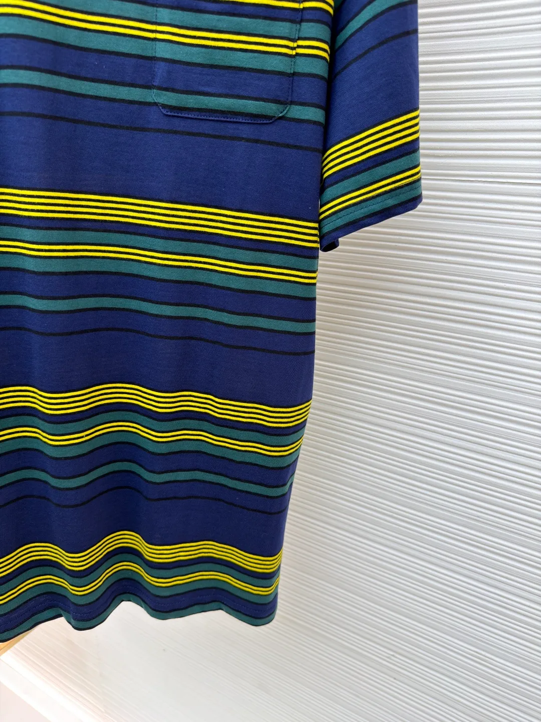 MIUMIU yellow, green and blue striped round neck short sleeves ●Original version: purchased and developed by 4755 ●Item number: 1681739-A10 ●Fabric: Jacquard striped knitted fabric ●Technology: Wool jacquard production ●Color: yellow, green and blue ●Version: Fitted version ●Weight: about 185 grams ●Size: XS-S-M-L ●Description: Using 32S jacquard stripe technology special textile compact cotton , 145g; with 32S double yarn frame, 380g. The fabric is made of 32-count combed cotton yarn and has been processed by compact spinning technology, so that the yarn fibers are tightly arranged and impurities and hairiness are significantly reduced. The fabric structure is denser and smoother. It not only feels delicate and smooth, but its wear resistance and anti-pilling performance is also far superior to ordinary cotton fabrics. The weight of the fabric ensures that the fabric has good durability while maintaining the natural breathability and skin-friendly properties of cotton. It is very suitable for spring, summer and transitional seasons, and achieves the unity of comfort and quality. The striped effect is achieved through plain knitting technology where colored yarns are alternately woven. This is different from later printing. The color is firm and long-lasting, and the striped edges are clear and neat. The design that combines simple stripes with the possible jacquard texture of the underlying fabric increases the visual layering, avoids monotony, and embodies the design idea of ​​finding sophistication in simplicity. The wool jacquard logo process is a high-end technology that weaves the brand logo directly into the fabric. The warp and weft yarns of the loom are controlled by computer programming, and yarns of different colors are interwoven to form precise and clear patterns on the surface of the sweater. The jacquard process makes the logo and logo fabric seamlessly integrated, with a smooth touch and no bulges, and clear and seamless edges, which greatly improves wearing comfort and aesthetics. The overall wiring is straight and delicate, the fabric is comfortable and soft, and the color is consistent without color difference. It can be matched with the same style to create a fashionable look and control various occasions. Customized accessories, complete with three standards, same style for men and women!