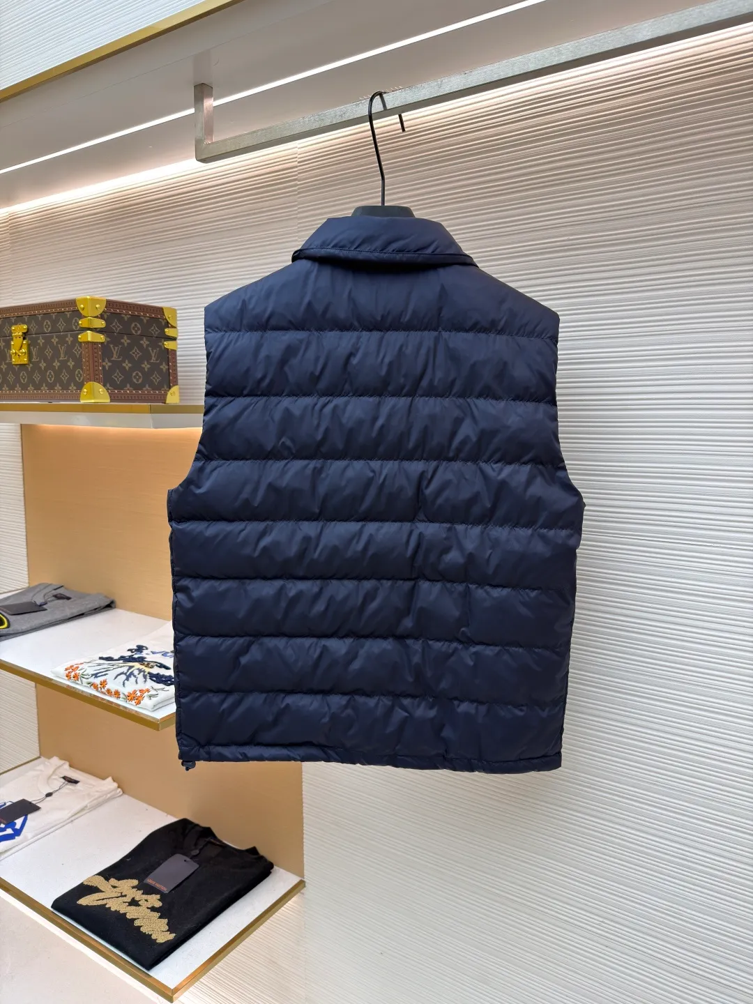 MIUMIU rib down lapel vest ●Original version: Purchased and developed for 12999 ●Item number: 1681785-C05 ●Fabric: goose down fabric ●Technology: mechanical down filling ●Color: navy blue ●Version: fitted version ●Weight: about 350 grams ●Size: 36-38-40-42 ●Description: Down anti-drilling liner is a kind of inner liner specially used for down jackets. It is usually made of high-density, anti-drilling down and good breathability materials. It can effectively prevent down from drilling out while maintaining the warmth and breathability of down jackets. Goose down filling is a high-quality filling in down jackets. It is rich in down, and because goose down has a higher loft, it can lock in more air, making the down jacket warmer. Down is soft and delicate. It feels soft and comfortable when worn on the human body, without the foreign body feeling caused by other fillings. After aurora printing, the pattern containing special additives is heat-pressed and transferred to the fabric in the form of a film, and the process parameters are adjusted to give it a slightly aged texture. This not only achieves the decorative purpose of the brand logo, but also avoids the stiffness often found in new technology fabrics because of its retro treatment of details. The design of the shirt collar allows the vest to increase its versatility. The snap closure provides a faster, smoother and more even force-on and take-off experience, especially when worn as an inner layer, making it less likely to snag with outer clothing. The elastic drawstring hem can be tightened by the drawstring, effectively preventing cold air from pouring in from the bottom and locking in body heat. The flap pocket is a classic outdoor functional design that prevents rain, wind and snow from entering the pocket, and is equipped with buttons for a more durable and quieter closure.