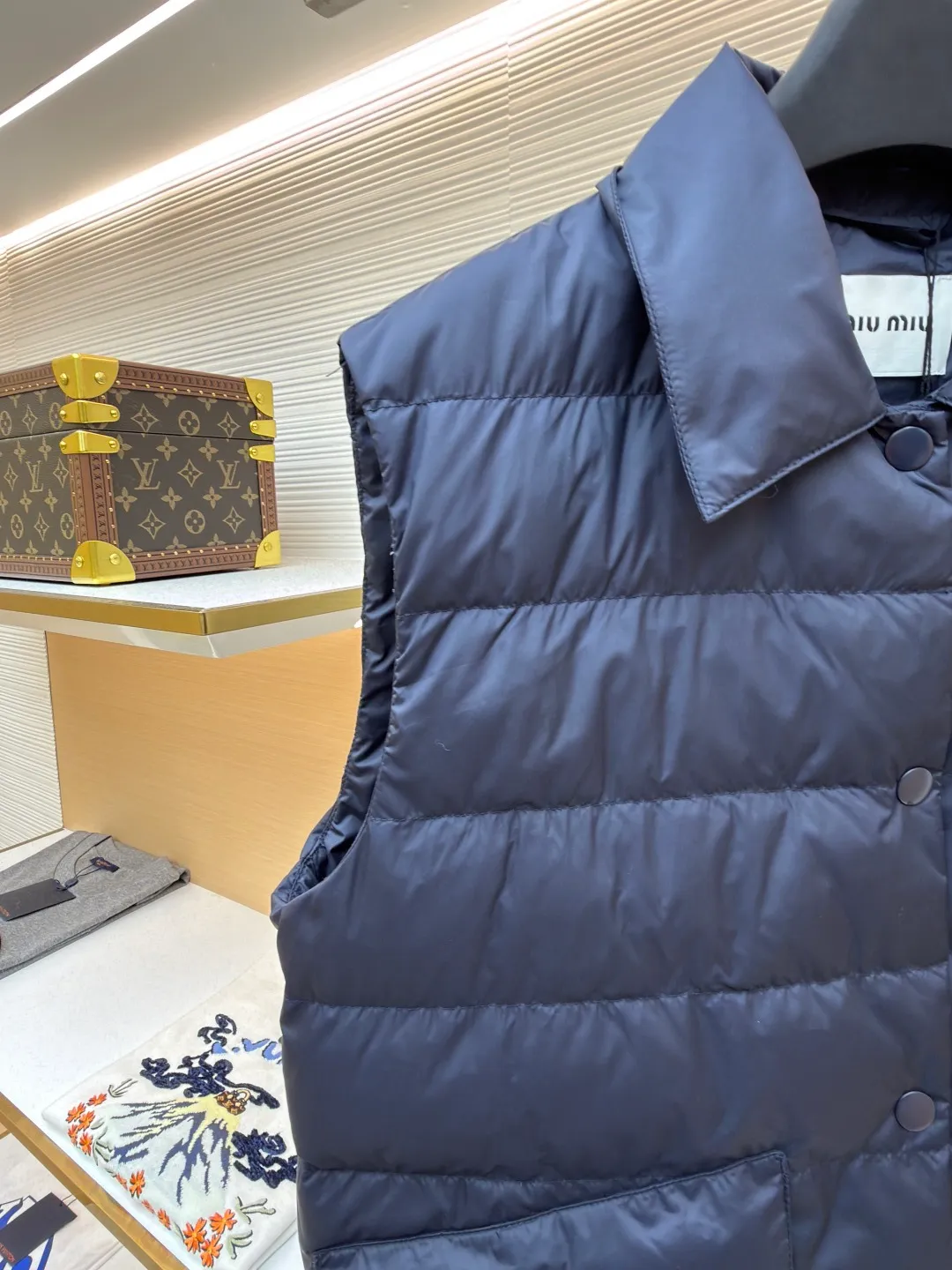 MIUMIU rib down lapel vest ●Original version: Purchased and developed for 12999 ●Item number: 1681785-C05 ●Fabric: goose down fabric ●Technology: mechanical down filling ●Color: navy blue ●Version: fitted version ●Weight: about 350 grams ●Size: 36-38-40-42 ●Description: Down anti-drilling liner is a kind of inner liner specially used for down jackets. It is usually made of high-density, anti-drilling down and good breathability materials. It can effectively prevent down from drilling out while maintaining the warmth and breathability of down jackets. Goose down filling is a high-quality filling in down jackets. It is rich in down, and because goose down has a higher loft, it can lock in more air, making the down jacket warmer. Down is soft and delicate. It feels soft and comfortable when worn on the human body, without the foreign body feeling caused by other fillings. After aurora printing, the pattern containing special additives is heat-pressed and transferred to the fabric in the form of a film, and the process parameters are adjusted to give it a slightly aged texture. This not only achieves the decorative purpose of the brand logo, but also avoids the stiffness often found in new technology fabrics because of its retro treatment of details. The design of the shirt collar allows the vest to increase its versatility. The snap closure provides a faster, smoother and more even force-on and take-off experience, especially when worn as an inner layer, making it less likely to snag with outer clothing. The elastic drawstring hem can be tightened by the drawstring, effectively preventing cold air from pouring in from the bottom and locking in body heat. The flap pocket is a classic outdoor functional design that prevents rain, wind and snow from entering the pocket, and is equipped with buttons for a more durable and quieter closure.