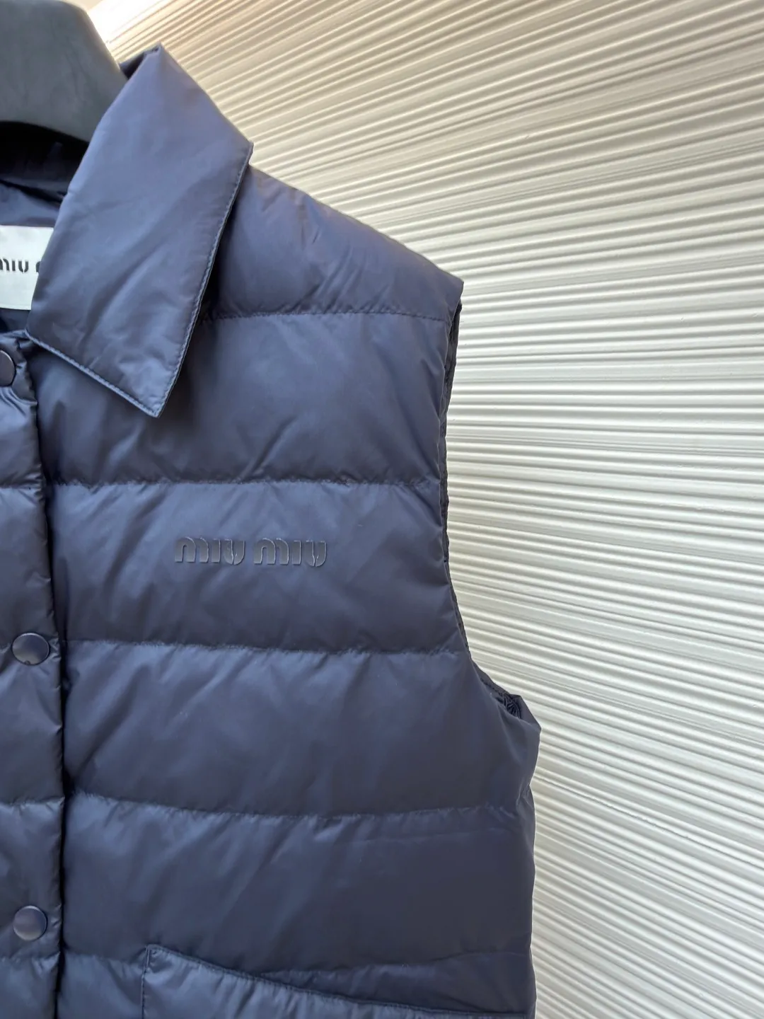 MIUMIU rib down lapel vest ●Original version: Purchased and developed for 12999 ●Item number: 1681785-C05 ●Fabric: goose down fabric ●Technology: mechanical down filling ●Color: navy blue ●Version: fitted version ●Weight: about 350 grams ●Size: 36-38-40-42 ●Description: Down anti-drilling liner is a kind of inner liner specially used for down jackets. It is usually made of high-density, anti-drilling down and good breathability materials. It can effectively prevent down from drilling out while maintaining the warmth and breathability of down jackets. Goose down filling is a high-quality filling in down jackets. It is rich in down, and because goose down has a higher loft, it can lock in more air, making the down jacket warmer. Down is soft and delicate. It feels soft and comfortable when worn on the human body, without the foreign body feeling caused by other fillings. After aurora printing, the pattern containing special additives is heat-pressed and transferred to the fabric in the form of a film, and the process parameters are adjusted to give it a slightly aged texture. This not only achieves the decorative purpose of the brand logo, but also avoids the stiffness often found in new technology fabrics because of its retro treatment of details. The design of the shirt collar allows the vest to increase its versatility. The snap closure provides a faster, smoother and more even force-on and take-off experience, especially when worn as an inner layer, making it less likely to snag with outer clothing. The elastic drawstring hem can be tightened by the drawstring, effectively preventing cold air from pouring in from the bottom and locking in body heat. The flap pocket is a classic outdoor functional design that prevents rain, wind and snow from entering the pocket, and is equipped with buttons for a more durable and quieter closure.