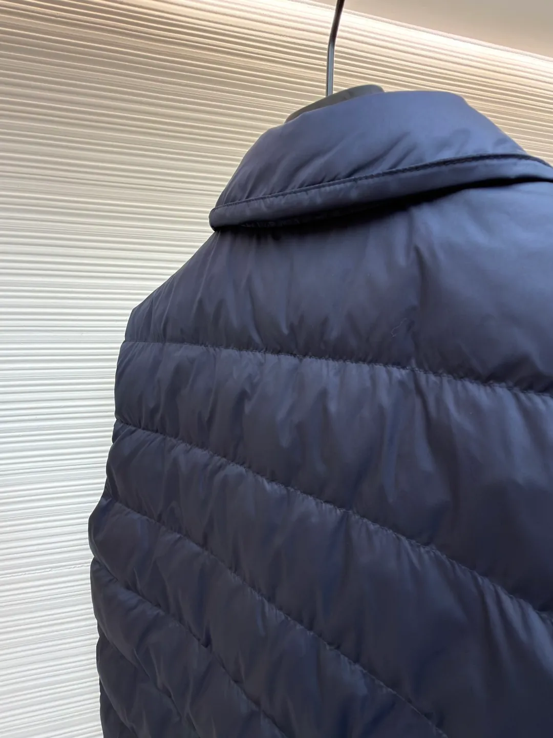 MIUMIU rib down lapel vest ●Original version: Purchased and developed for 12999 ●Item number: 1681785-C05 ●Fabric: goose down fabric ●Technology: mechanical down filling ●Color: navy blue ●Version: fitted version ●Weight: about 350 grams ●Size: 36-38-40-42 ●Description: Down anti-drilling liner is a kind of inner liner specially used for down jackets. It is usually made of high-density, anti-drilling down and good breathability materials. It can effectively prevent down from drilling out while maintaining the warmth and breathability of down jackets. Goose down filling is a high-quality filling in down jackets. It is rich in down, and because goose down has a higher loft, it can lock in more air, making the down jacket warmer. Down is soft and delicate. It feels soft and comfortable when worn on the human body, without the foreign body feeling caused by other fillings. After aurora printing, the pattern containing special additives is heat-pressed and transferred to the fabric in the form of a film, and the process parameters are adjusted to give it a slightly aged texture. This not only achieves the decorative purpose of the brand logo, but also avoids the stiffness often found in new technology fabrics because of its retro treatment of details. The design of the shirt collar allows the vest to increase its versatility. The snap closure provides a faster, smoother and more even force-on and take-off experience, especially when worn as an inner layer, making it less likely to snag with outer clothing. The elastic drawstring hem can be tightened by the drawstring, effectively preventing cold air from pouring in from the bottom and locking in body heat. The flap pocket is a classic outdoor functional design that prevents rain, wind and snow from entering the pocket, and is equipped with buttons for a more durable and quieter closure.