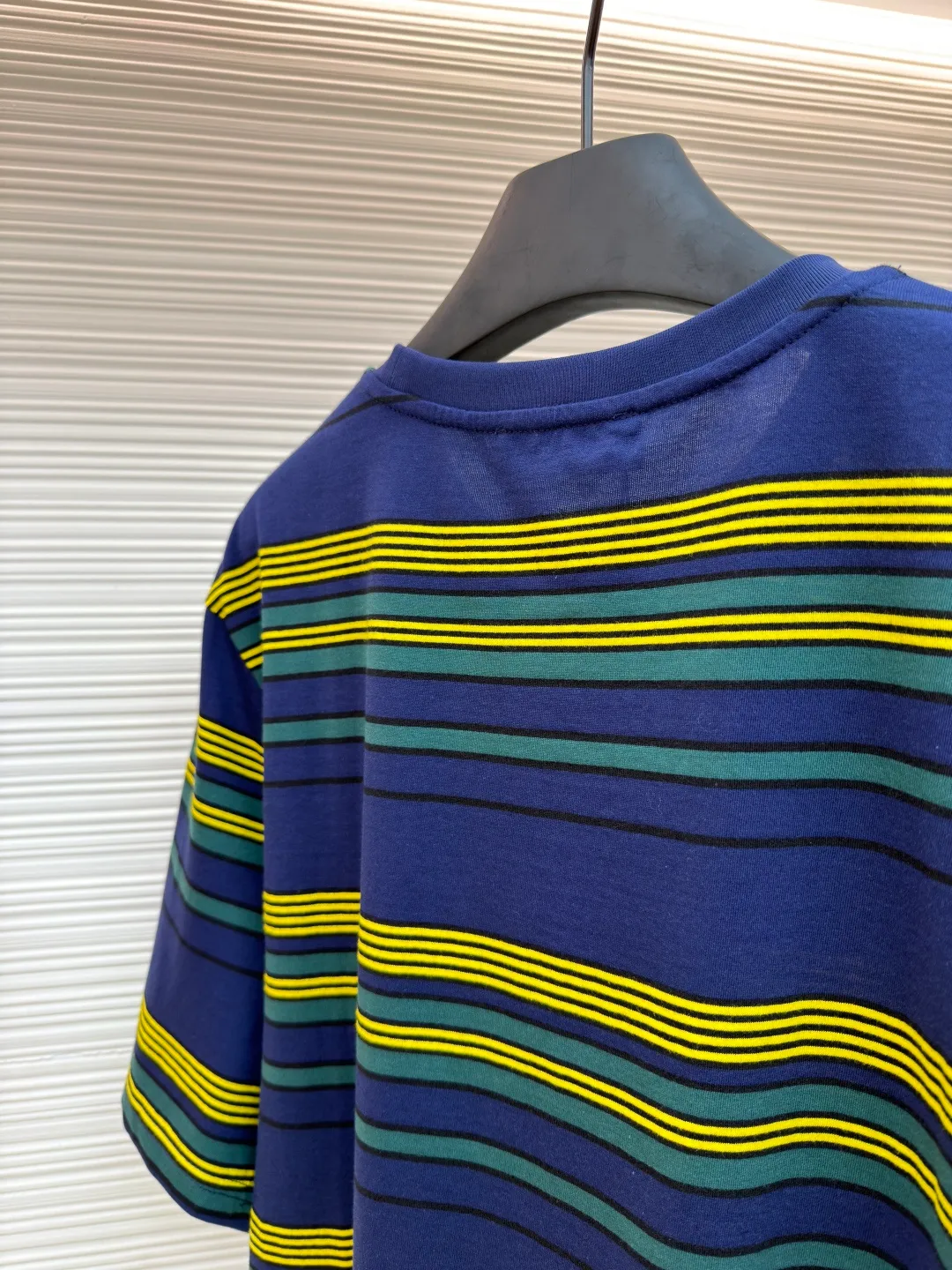 MIUMIU yellow, green and blue striped round neck short sleeves ●Original version: purchased and developed by 4755 ●Item number: 1681739-A10 ●Fabric: Jacquard striped knitted fabric ●Technology: Wool jacquard production ●Color: yellow, green and blue ●Version: Fitted version ●Weight: about 185 grams ●Size: XS-S-M-L ●Description: Using 32S jacquard stripe technology special textile compact cotton , 145g; with 32S double yarn frame, 380g. The fabric is made of 32-count combed cotton yarn and has been processed by compact spinning technology, so that the yarn fibers are tightly arranged and impurities and hairiness are significantly reduced. The fabric structure is denser and smoother. It not only feels delicate and smooth, but its wear resistance and anti-pilling performance is also far superior to ordinary cotton fabrics. The weight of the fabric ensures that the fabric has good durability while maintaining the natural breathability and skin-friendly properties of cotton. It is very suitable for spring, summer and transitional seasons, and achieves the unity of comfort and quality. The striped effect is achieved through plain knitting technology where colored yarns are alternately woven. This is different from later printing. The color is firm and long-lasting, and the striped edges are clear and neat. The design that combines simple stripes with the possible jacquard texture of the underlying fabric increases the visual layering, avoids monotony, and embodies the design idea of ​​finding sophistication in simplicity. The wool jacquard logo process is a high-end technology that weaves the brand logo directly into the fabric. The warp and weft yarns of the loom are controlled by computer programming, and yarns of different colors are interwoven to form precise and clear patterns on the surface of the sweater. The jacquard process makes the logo and logo fabric seamlessly integrated, with a smooth touch and no bulges, and clear and seamless edges, which greatly improves wearing comfort and aesthetics. The overall wiring is straight and delicate, the fabric is comfortable and soft, and the color is consistent without color difference. It can be matched with the same style to create a fashionable look and control various occasions. Customized accessories, complete with three standards, same style for men and women!