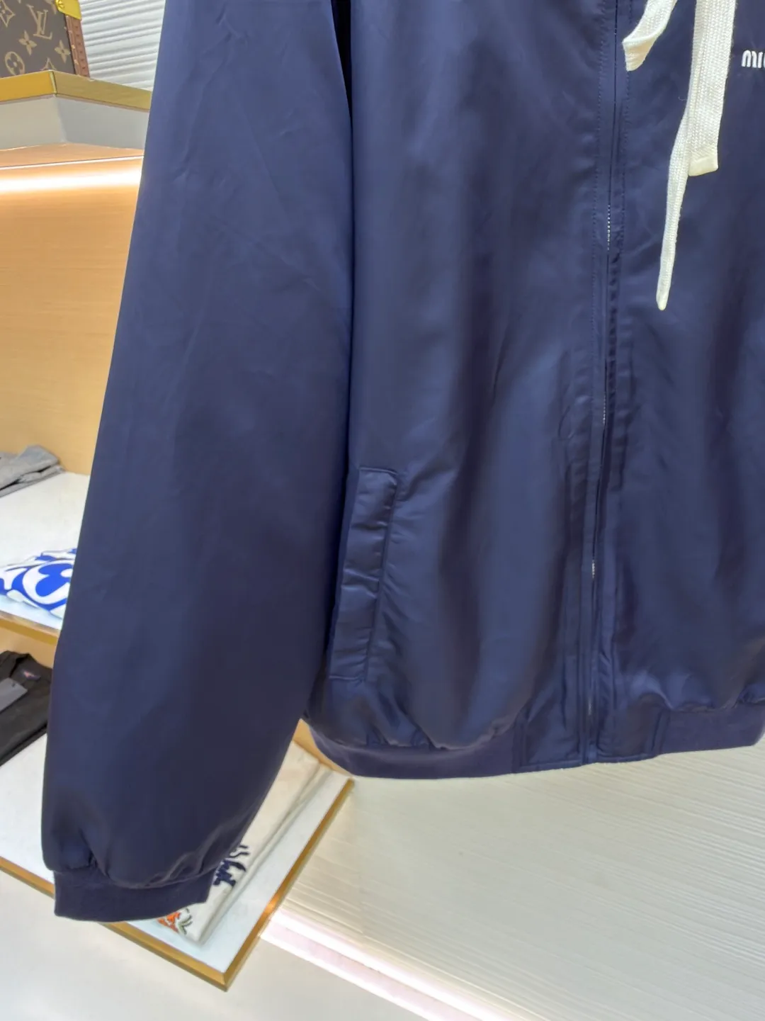 MIUMIU reversible technical fabric and fleece jacket ●Original version: 28200 purchase and development ●Item number: 1682256-C00 ●Fabric: wool blended anti-static plush fabric ●Technology: high temperature pre-shrunk production ●Color: blue/grey ●Version: fitted version ●Weight: about 890 grams ●Size: 36-38-40-42 ●Description: This Miu The Miu navy jacket is made of high-density polyester fabric, which has been treated with water-repellent treatment. The surface has a fine matte texture and has good windproof performance. The body is cut with raglan sleeves, and the three-dimensional patterning technology is used to make the shoulder lines more ergonomic, and there is no sense of restraint when moving. The neckline is spliced ​​with gray fleece lining, which is reinforced with double-needle hemming technology. The drawstring is made of natural cotton rope and has been brushed. The texture is soft and waxy and not easy to deform. The front is equipped with a customized metal zipper, and the smoothness of the gear rail has been tested multiple times. The zipper puller and brand logo are both made by laser engraving. The ribbed edges on the hem and cuffs are made of spandex blended material and are pre-shrunk to prevent them from loosening after long-term wear. The overall stitching uses dual processes of flat turning and overlocking. The stitching is even and fine, reaching the high standard of 12 stitches per inch, ensuring both a stiff silhouette and durability. The overall wiring is straight and delicate, the fabric is comfortable and soft, and the color is consistent without color difference. It can be matched with the same style to create a fashionable look and control various occasions. Customized accessories, complete with three standards, same style for men and women!