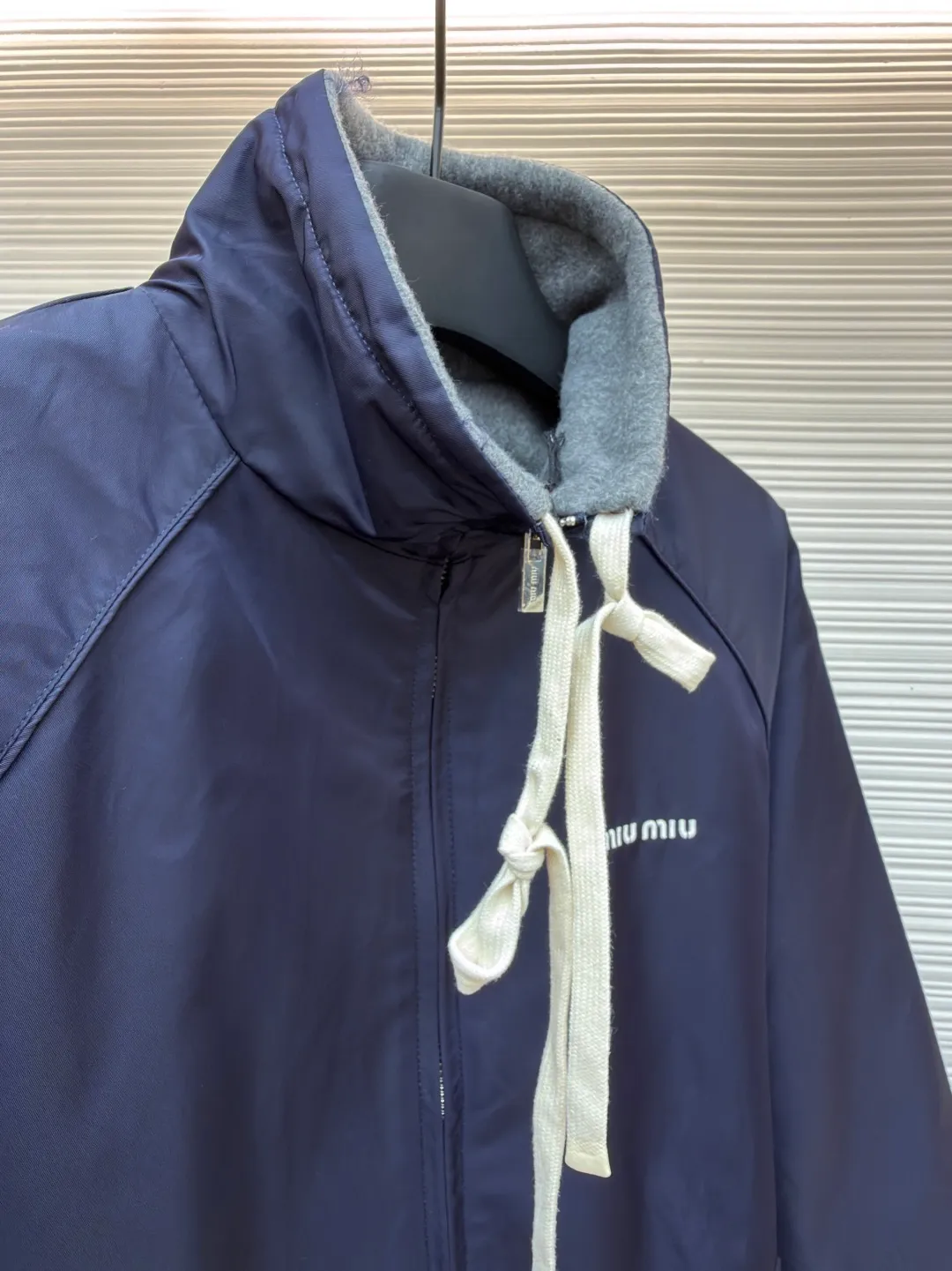 MIUMIU reversible technical fabric and fleece jacket ●Original version: 28200 purchase and development ●Item number: 1682256-C00 ●Fabric: wool blended anti-static plush fabric ●Technology: high temperature pre-shrunk production ●Color: blue/grey ●Version: fitted version ●Weight: about 890 grams ●Size: 36-38-40-42 ●Description: This Miu The Miu navy jacket is made of high-density polyester fabric, which has been treated with water-repellent treatment. The surface has a fine matte texture and has good windproof performance. The body is cut with raglan sleeves, and the three-dimensional patterning technology is used to make the shoulder lines more ergonomic, and there is no sense of restraint when moving. The neckline is spliced ​​with gray fleece lining, which is reinforced with double-needle hemming technology. The drawstring is made of natural cotton rope and has been brushed. The texture is soft and waxy and not easy to deform. The front is equipped with a customized metal zipper, and the smoothness of the gear rail has been tested multiple times. The zipper puller and brand logo are both made by laser engraving. The ribbed edges on the hem and cuffs are made of spandex blended material and are pre-shrunk to prevent them from loosening after long-term wear. The overall stitching uses dual processes of flat turning and overlocking. The stitching is even and fine, reaching the high standard of 12 stitches per inch, ensuring both a stiff silhouette and durability. The overall wiring is straight and delicate, the fabric is comfortable and soft, and the color is consistent without color difference. It can be matched with the same style to create a fashionable look and control various occasions. Customized accessories, complete with three standards, same style for men and women!