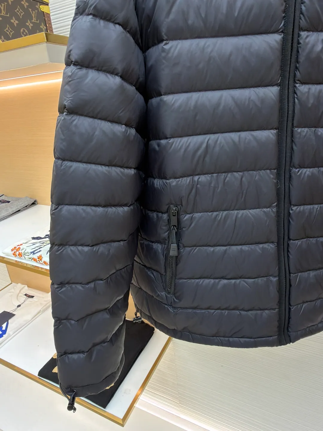 MIU MIU hooded down jacket ●Item number: 1681314-C55 ●Material: white duck down fabric ●Technology: mechanical down filling ●Color: black ●Version: fitted version ●Weight: about 615 grams ●Size: S-M-L-XL ●Description: This is a light down jacket from the MiuMiu brand. Its craftsmanship details are as follows: It is made of exquisite pongé fabric made of 100% recycled polyester fiber. This fabric has good windproof performance, and at the same time has a delicate texture and a high-end luster. It has high fluffiness, excellent warmth retention and is very light overall, allowing the wearer to gain warmth without any heavy burden. It has a three-dimensional cut and a neat silhouette. Precision stitching technology is used during sewing to form regular quilting lines, which not only serves to fix the down, but also enhances the structure and design of the garment. The stitches are fine and even, and the seams are smooth, reflecting the exquisite craftsmanship of garment making. Equipped with a customized wax zipper, the zipper is smooth and durable, and the zipper puller has brand details and a high-quality feel. The hooded design fits the head and increases warmth; the drawstring cuffs can be adjusted according to needs to prevent cold wind from entering; the elastic drawstring at the hem can adjust the looseness of the hem, improving the comfort and practicality of wearing; there is the brand's embroidered logo on the chest, with fine craftsmanship and highlighting the brand identity.