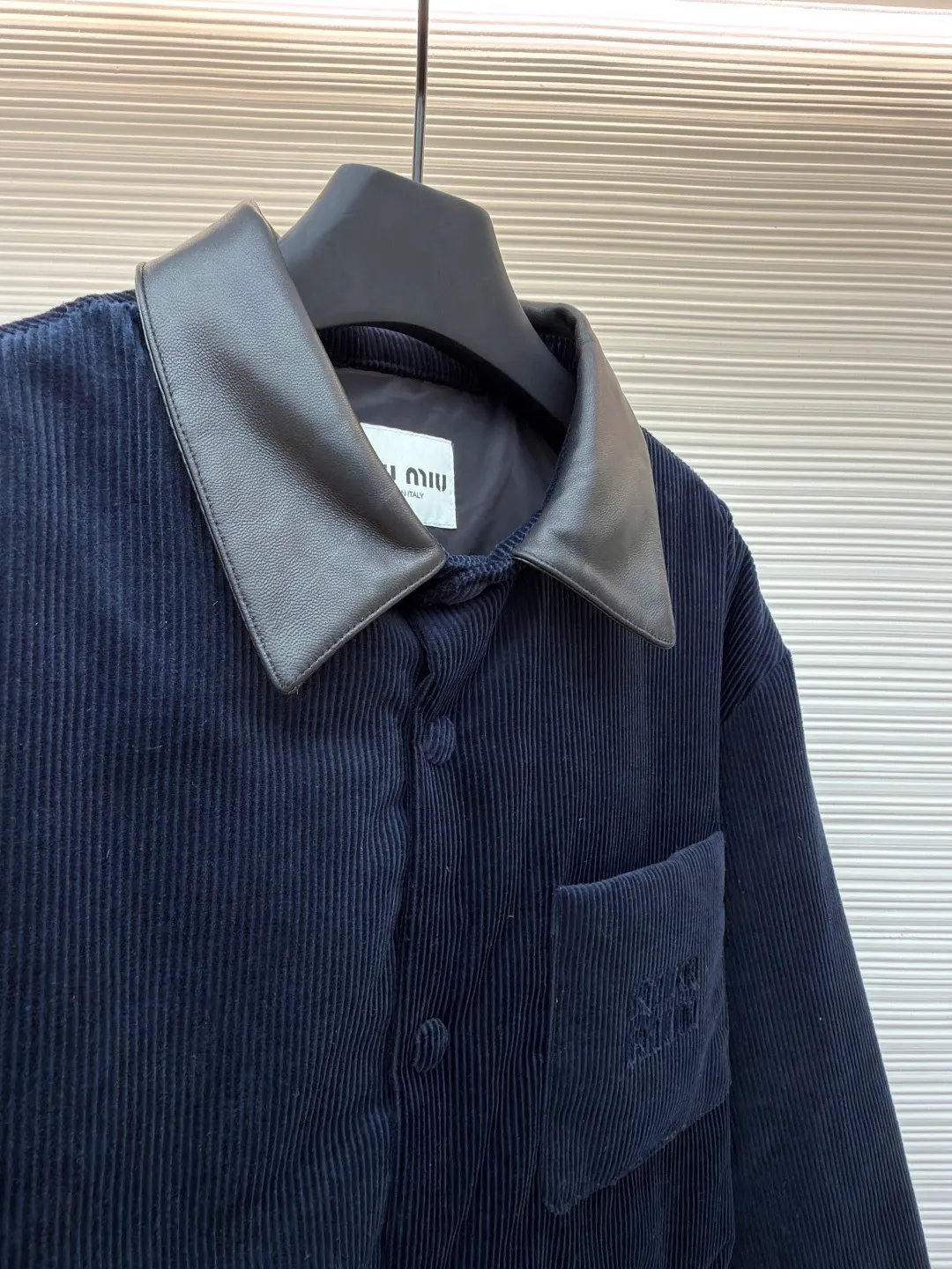 MIUMIU leather collar corduroy down jacket ●Original version: purchased and developed by 16097 ●Item number: 1681743-C75 ●Fabric: corduroy fabric ●Technology: patch embroidery production ●Color: navy blue ●Version: fitted version ●Weight: about 935 grams ●Size: 46-48-50-52 ●Description: When embroidery of the same color quietly grows among the corduroy textures - MIUMIU redefines winter elegance with "hidden beauty", making warmth a tacit whisper. Classic fine-ribbed corduroy wraps the body, with down like clouds lurking between the convex and convex warps and wefts. 90% white duck down silently resists the cold wind, but lets the fabric speak for itself - every velvet is the path of sunlight, and every ridge is a fortress built by warmth. The custom-made lambskin lapel falls along the curve of the neck, making it breathable like a second skin. Cold leather and soft suede complete a material game on the collar, and the sound of metal snaps opening and closing becomes the only punctuation mark in this dialogue. Exquisite appliqué technology performs visual magic on the left breast pocket: the embroidered letter patches are laser cut and shaped to create an embossed texture and clear fonts. Each patch undergoes 5 layers of anti-wrinkle treatment to ensure that it retains its original shape after washing. The embroidered fabric of the same color as the fabric runs along the MIUMIU logo, with only subtle gloss differences and raised stitches to enhance visual recognition. The overall wiring is straight and delicate, the fabric is comfortable and soft, and the color is consistent without color difference. It can be matched with the same style to create a fashionable look and control various occasions. Customized accessories, complete with three standards, same style for men and women!