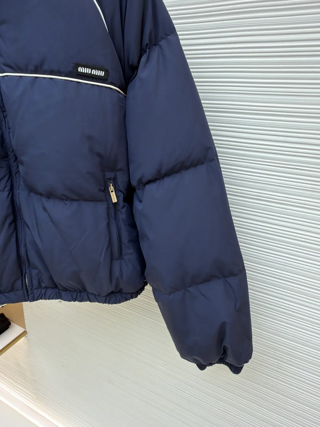 MIUMIU logo down jacket ●Original version: purchased and developed at 18695 ●Item number: 1861323-C95 ●Fabric: white duck down fabric ●Technology: mechanical down filling ●Color: navy ●Type: fitted version ●Weight: about 810 grams ●Size: 46-48-50-52 ●Description: Different from ordinary fabrics, custom-developed high-count and high-density woven fabrics. Imported computerized down filling equipment is used to ensure that the amount of down filling in each independent quilting grid is accurate and even, avoiding local holes or agglomerations, thereby ensuring the overall flatness, uniformity of warmth and long-lasting fluffiness of the down jacket. From the treatment of the interior, the firmness of the stitching of the zippers, to the precise positioning of decorative elements such as logos, the factory's craftsmanship ensures that the entire piece has impeccable finish and durable quality, making it a long-term wardrobe treasure worth owning. The overall wiring is straight and delicate, the fabric is comfortable and soft, and the color is consistent without color difference. It can be matched with the same style to create a fashionable look and control various occasions. Customized accessories, complete with three standards, same style for men and women!