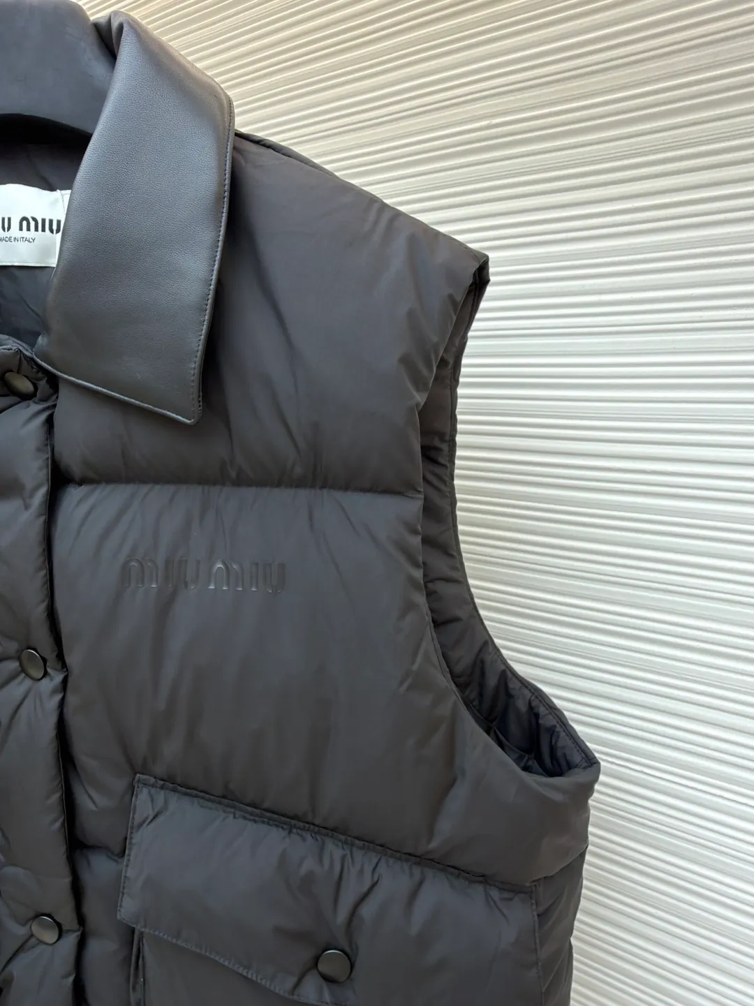 MIUMIU technology ponge down vest ●Item number: 1681319-C65 ●Material: white duck down fabric ●Technology: mechanical down filling ●Color: black ●Version: fitted version ●Weight: about 450 grams ●Size: S-M-L ●Description: This vest is made of lightweight and durable nylon fabric with down filling, taking into account warmth and fashion. The collar is made of genuine leather to improve the overall texture and warmth. The outer layer of high-density nylon is windproof and waterproof, lightweight and wear-resistant. The inner layer is filled with down, which has high fluffiness and warmth retention. It is made of national standard 90 white duck down and has a filling capacity of 190 grams to ensure excellent warmth retention. The down has been strictly screened and processed and is not easy to be drilled, ensuring durability. The letter pattern is displayed on the breast bag piece through glue printing. The printer scrapes the print 10 times to ensure the printing thickness, forming a micro-three-dimensional convex structure. The scraper pressure is even and the firmness is improved. After being cured at high temperature, the pigment is combined with the fabric fibers and is not easy to fall off due to friction. The overall wiring is straight and delicate, the fabric is comfortable and soft, and the color is consistent without color difference. It can be matched with the same style to create a fashionable look and control various occasions. Customized accessories, complete with three standards, same style for men and women!