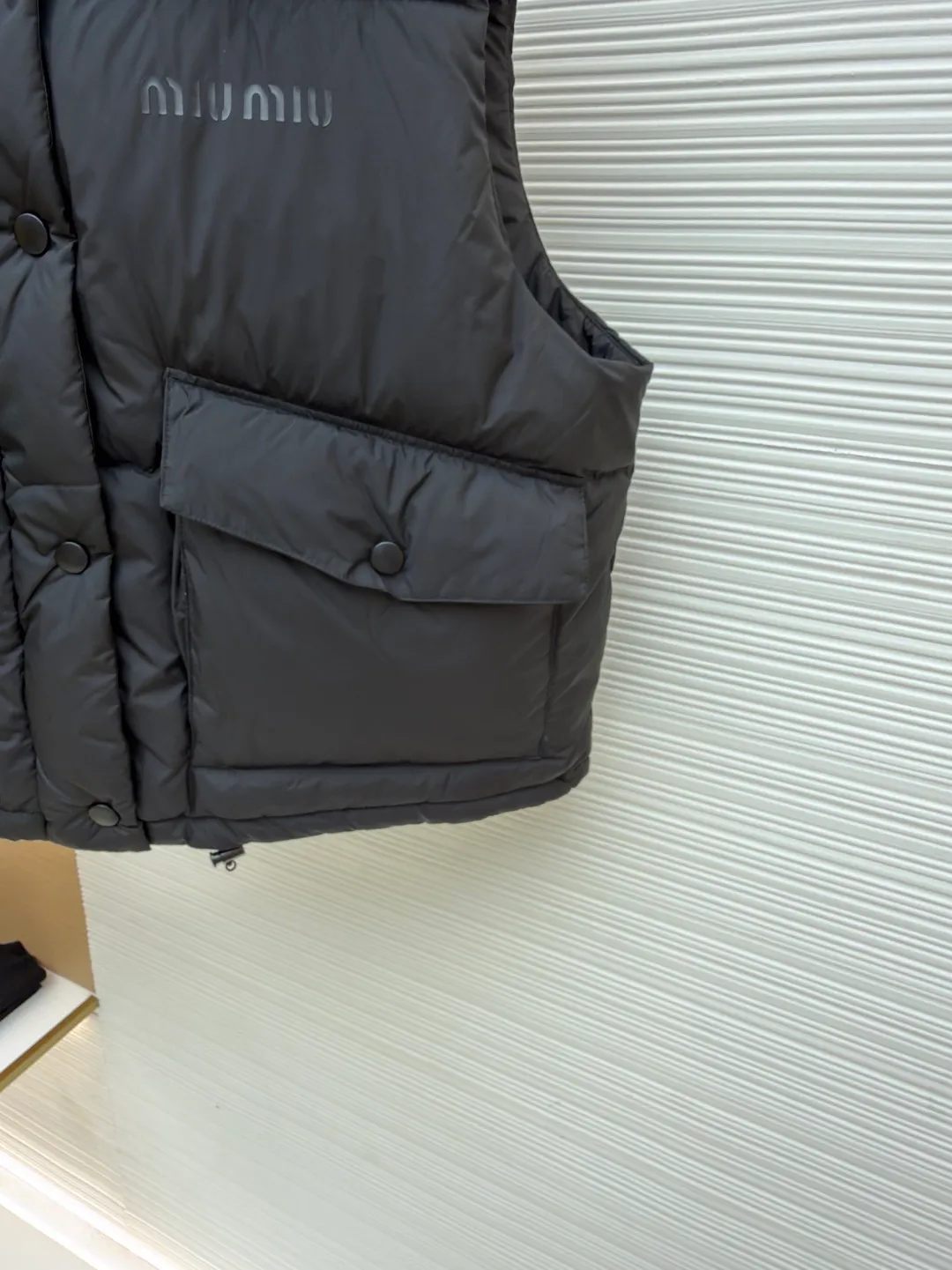 MIUMIU technology ponge down vest ●Item number: 1681319-C65 ●Material: white duck down fabric ●Technology: mechanical down filling ●Color: black ●Version: fitted version ●Weight: about 450 grams ●Size: S-M-L ●Description: This vest is made of lightweight and durable nylon fabric with down filling, taking into account warmth and fashion. The collar is made of genuine leather to improve the overall texture and warmth. The outer layer of high-density nylon is windproof and waterproof, lightweight and wear-resistant. The inner layer is filled with down, which has high fluffiness and warmth retention. It is made of national standard 90 white duck down and has a filling capacity of 190 grams to ensure excellent warmth retention. The down has been strictly screened and processed and is not easy to be drilled, ensuring durability. The letter pattern is displayed on the breast bag piece through glue printing. The printer scrapes the print 10 times to ensure the printing thickness, forming a micro-three-dimensional convex structure. The scraper pressure is even and the firmness is improved. After being cured at high temperature, the pigment is combined with the fabric fibers and is not easy to fall off due to friction. The overall wiring is straight and delicate, the fabric is comfortable and soft, and the color is consistent without color difference. It can be matched with the same style to create a fashionable look and control various occasions. Customized accessories, complete with three standards, same style for men and women!