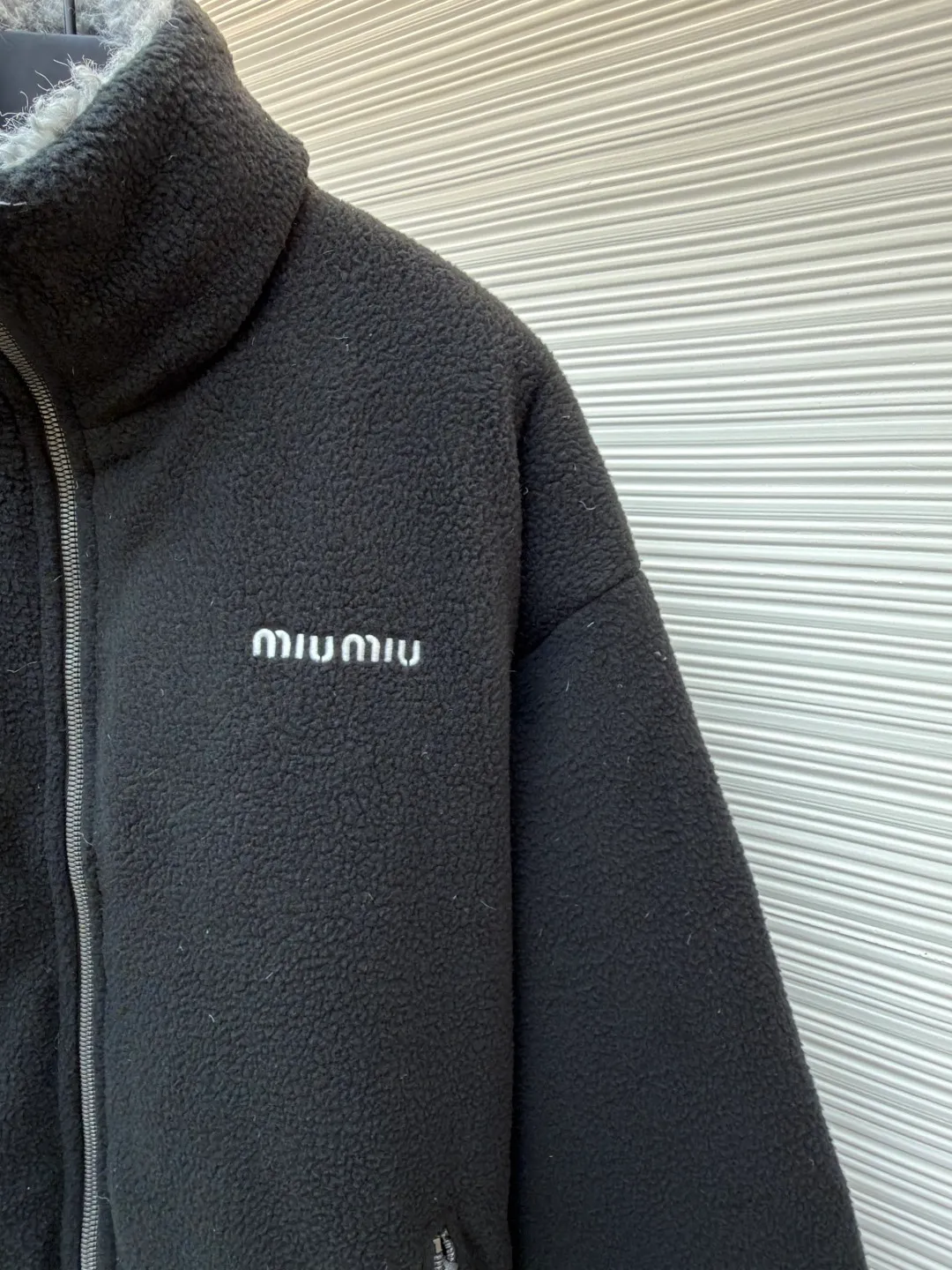 MIUMIU Polar Fleece Collar Down Jacket ●Original version: purchased and developed at 16999 ●Item number: 1681395-C65 ●Fabric: polar fleece fabric ●Technology: made on positioning cutting machine ●Color: black ●Version: fitted version ●Weight: about 945 grams ●Size: 38-40-42-44 ●Description: This jacket is made of high-quality polar fleece fabric and treated with a special fleece process. It feels soft and fluffy and has excellent warmth retention. The collar is made of imitation lambswool and is made through flocking technology, forming a texture contrast with the polar fleece fabric. The main zipper is a custom-made metal zipper, which is smooth and durable; the zippers of the zipper pockets on both sides are made of the same material as the main zipper, combining practicality and design. The brand logo adopts exquisite embroidery technology, and the stitching is fine and firm. The drawstring at the hem adopts a metal buckle and can be adjusted for tightness. The overall sewing adopts flat seam technology, the stitch spacing is even, and the seams of the body are smooth and snug. From the comfortable texture of the fabric to the craftsmanship of the details, it reflects the brand's dual pursuit of fashion and quality. It is a single product with both warmth and design. The overall wiring is straight and delicate, the fabric is comfortable and soft, and the color is consistent without color difference. It can be matched with the same style to create a fashionable look and control various occasions. Customized accessories, complete with three standards, same style for men and women!