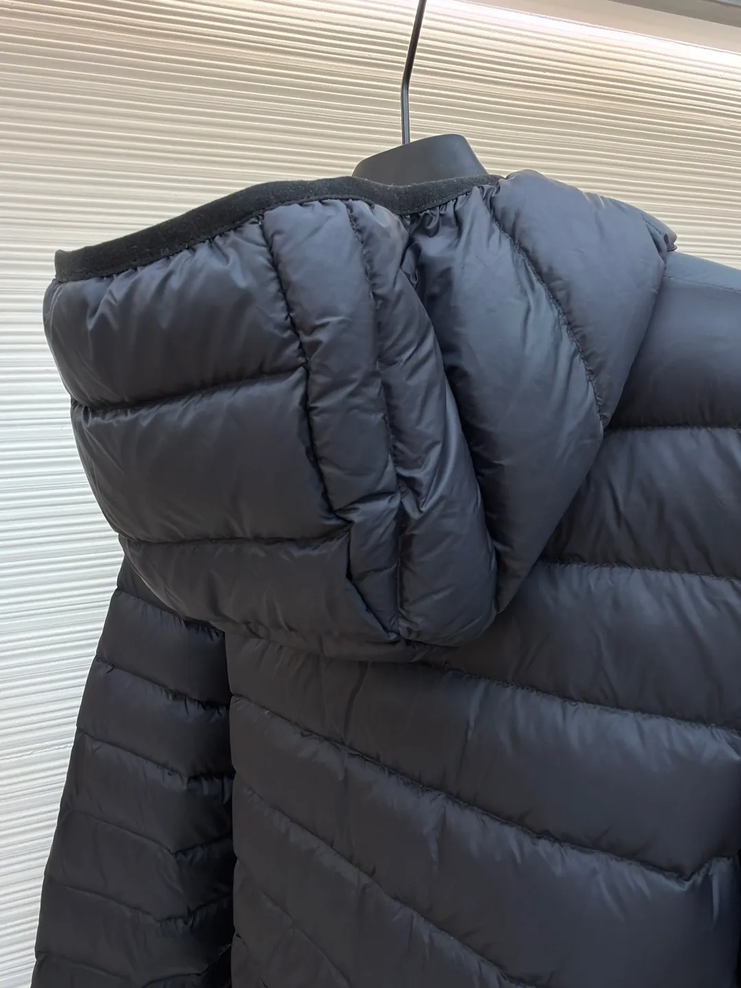 MIU MIU hooded down jacket ●Item number: 1681314-C55 ●Material: white duck down fabric ●Technology: mechanical down filling ●Color: black ●Version: fitted version ●Weight: about 615 grams ●Size: S-M-L-XL ●Description: This is a light down jacket from the MiuMiu brand. Its craftsmanship details are as follows: It is made of exquisite pongé fabric made of 100% recycled polyester fiber. This fabric has good windproof performance, and at the same time has a delicate texture and a high-end luster. It has high fluffiness, excellent warmth retention and is very light overall, allowing the wearer to gain warmth without any heavy burden. It has a three-dimensional cut and a neat silhouette. Precision stitching technology is used during sewing to form regular quilting lines, which not only serves to fix the down, but also enhances the structure and design of the garment. The stitches are fine and even, and the seams are smooth, reflecting the exquisite craftsmanship of garment making. Equipped with a customized wax zipper, the zipper is smooth and durable, and the zipper puller has brand details and a high-quality feel. The hooded design fits the head and increases warmth; the drawstring cuffs can be adjusted according to needs to prevent cold wind from entering; the elastic drawstring at the hem can adjust the looseness of the hem, improving the comfort and practicality of wearing; there is the brand's embroidered logo on the chest, with fine craftsmanship and highlighting the brand identity.