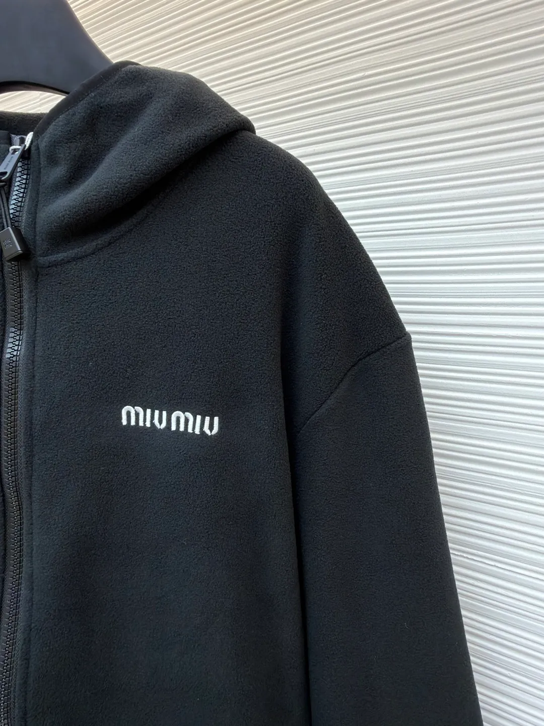 MIUMIU polar fleece embroidered jacket ●Original version: purchased and developed by 14859 ●Item number: 1680859-A95 ●Fabric: polar fleece fabric ●Technology: embroidery production ●Version: fitted version ●Weight: about 585 grams ●Size: 46-48-50-52 ●Description: The polyester filament passes through a circular knitting machine, and the warp and weft yarns are woven into each other into a double-sided knitted structure. The front and back are flat loops. The polar fleece fabric is formed after a series of processes such as dyeing, raising, carding, shearing, and polarization. The suede texture is soft and the fiber characteristics make it almost non-absorbent. It can quickly drain sweat to the outer layer of the fabric and evaporate quickly, maintaining good breathability. The suede surface can lock the air and form a stagnant air layer around the body, effectively preventing heat loss and providing good warmth retention properties. By setting an extremely high stitch density on the computer embroidery machine, the fabric and backing are tightly fixed on the frame of the embroidery machine, with even and just the right tension. The double-axis linear guide drives the embroidery frame, and the frame moving accuracy can reach 0.01mm/P, ensuring precise positioning. The overall wiring is straight and delicate, the fabric is comfortable and soft, and the color is consistent without color difference. It can be matched with the same style to create a fashionable look and control various occasions. Customized accessories, complete with three standards, same style for men and women!