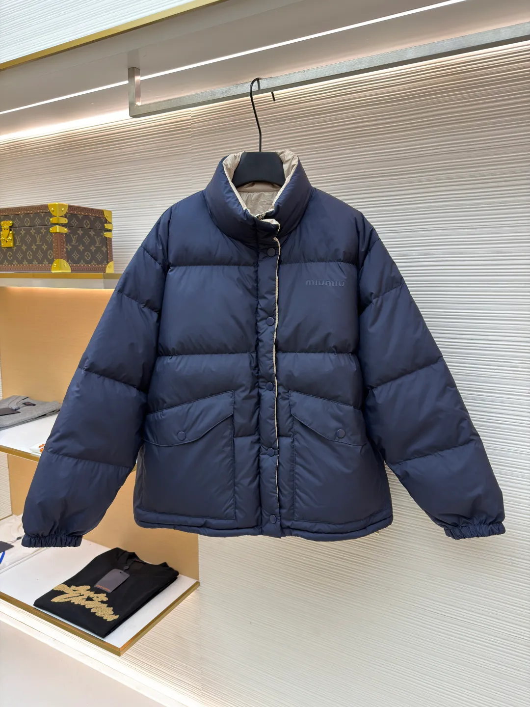 MIUMIU reversible stand collar down jacket ●Original version: purchased and developed by 21060 ●Item number: 1681385-D05 ●Fabric: white duck down fabric ●Technology: mechanical down filling ●Color: navy/khaki ●Version: fitted version ●Weight: about 675 grams ●Size: 36-38-40-42 ●Description: The filling is white duck down with 90% down content, which is one of the gold standards of down quality. "90% down content" means that the down content is extremely high and there are very few impurities such as feather stalks. The down tufts can capture more air and form an efficient thermal insulation layer, thus providing several times the loft and warmth of ordinary down while being lighter in weight. In the double-sided structure, ensuring that the down is evenly distributed between the two layers of fabric without clumping is the core challenge of the down filling process. The stand-up collar design not only improves the neatness of the shape, but also enhances the windproof and warm performance of the neck. Its internal structure needs to be stiff enough to maintain a three-dimensional shape, while at the same time ensuring the comfort of contact with the skin. The precision stitching in conjunction with the overall design not only plays a role in fixing the down and preventing displacement, but the uniformity, tension and pattern of the stitches have become important decorative elements, reflecting rigorous industrial aesthetics. The overall wiring is straight and delicate, the fabric is comfortable and soft, and the color is consistent without color difference. It can be matched with the same style to create a fashionable look and control various occasions. Customized accessories, complete with three standards, same style for men and women!
