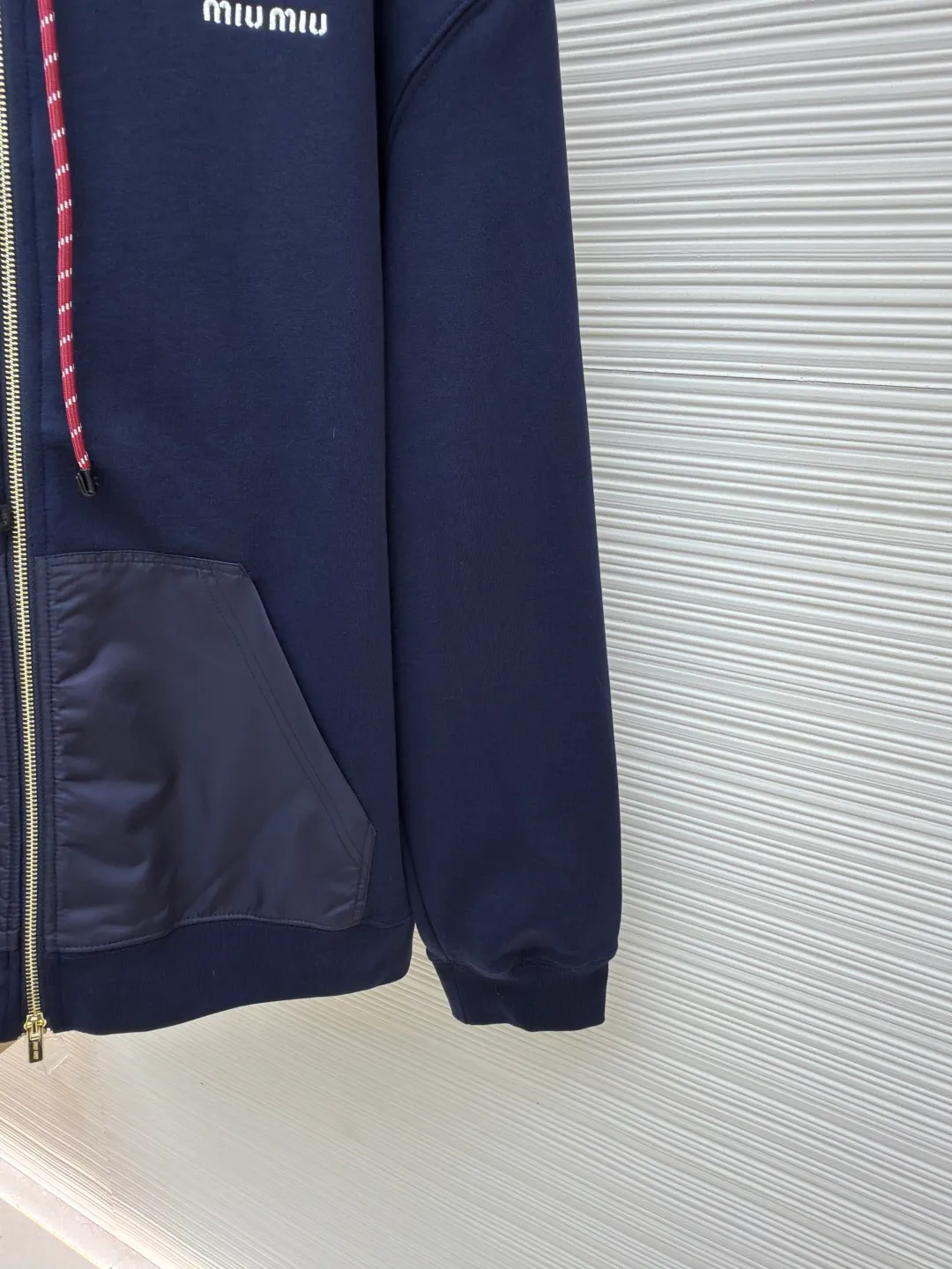 MIUMIU embroidered hooded sweatshirt ●Original version: purchased and developed by 13979 ●Item number: 1680807-B05 ●Fabric: fish scale fabric ●Technology: embroidery production ●Version: fitted version ●Weight: about 790 grams ●Size: S-M-L-XL ●Description: A single-sided fish-scale fabric woven with cotton as the base. The front is a smooth knitted surface, and the skin-contacting surface is formed into three-dimensional terry by the floating thread knitting technology of the knitting machine, which increases the fluffiness and has a delicate touch. The terry structure absorbs a large amount of water and evaporates quickly, so it is not easy to loosen and deform after repeated washing. The hat body and side pockets are made of nylon fabric, which is wear-resistant and has good wind resistance as the hat body. The 2*2 ribs formed by alternating longitudinal rows of front coils and longitudinal rows of back coils are still very elastic and have wide textures that fit the wrists and waist without a sense of restraint. The gaps between the coils allow air circulation without losing warmth. By actively interfering with the shrinkage potential of cotton fibers, the fabric is able to transition from changeable to stable, improving dimensional stability while being less prone to deformation and wrinkles. The high-precision calculation program system of the computerized embroidery machine controls the movement of the embroidery frame in the X/Y direction. At the same time, the needle shuttles up and down to embroider according to the set path. It automatically completes thread trimming, thread jumping and other actions to form a stitch track. It automatically adjusts the upper and lower thread tension to ensure that the stitches are smooth and free of floating threads, forming a high-precision letter pattern. The overall wiring is straight and delicate, the fabric is comfortable and soft, and the color is consistent without color difference. It can be matched with the same style to create a fashionable look and control various occasions. Customized accessories, complete with three standards, same style for men and women!