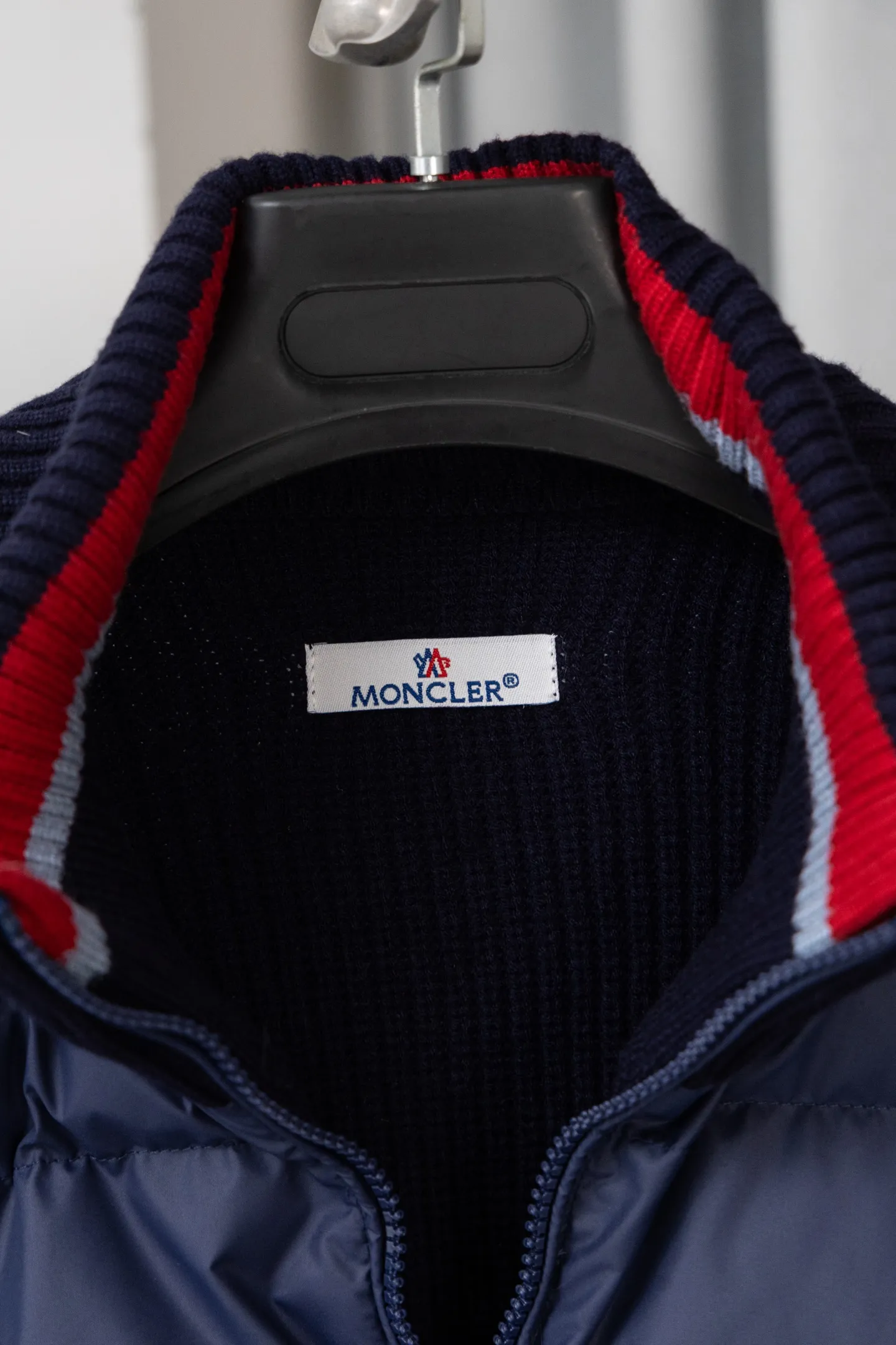 P560 Style number: M046 This is a knitted patchwork down jacket from Moncler. It combines the brand's high-end outdoor genes and fashion design. It is a luxurious item with both warmth and style in autumn and winter. Design highlights: Material splicing: Pure wool knitted sleeves are spliced ​​with a down front filled with 90 white duck down. The knitted part is soft and breathable, and the down part is fluffy and warm, achieving a dual fusion of style and function.  Detailed logo: The iconic Moncler badge pocket on the left arm is a classic embodiment of brand recognition; the stand-up collar design with a two-way zipper not only improves warmth, but also strengthens the neat styling.  Color embellishment: The contrasting red and blue stripes on the cuffs and hem inject vitality into the overall black tone, adding a retro college style charm. Craftsmanship and Quality: The down filling follows the European standard 90 down standard, with excellent fluffiness and down filling, with almost no stiff feeling. At the same time, it adopts the "line first and then separate down filling" process. The four-layer liner effectively prevents down from being drilled, and can maintain warmth even after long-term wear.  The knitted part is made of high-quality wool, which has a delicate touch and is not easily deformed. The splicing process with the down fabric is rigorous, showing a high-end texture level.  Style and Wearing This down jacket is based on the classic college style. The slim straight version can modify the body line and can be easily adapted to a variety of styles: it can be paired with jeans and casual shoes for a casual look on a daily basis. It can also be upgraded to an urban light luxury style by layering it with a turtleneck sweater inside and a suit outside. It is a key item in the winter wardrobe that is both practical and fashionable. Color: black, navy blue, sizes S-XL