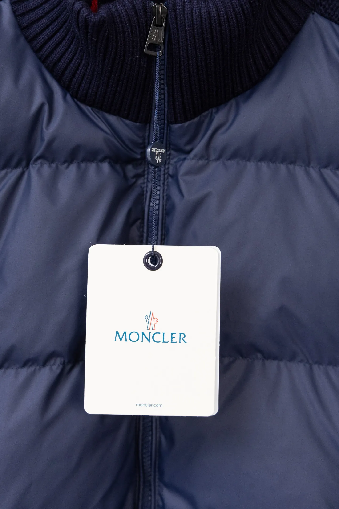 P560 Style number: M046 This is a knitted patchwork down jacket from Moncler. It combines the brand's high-end outdoor genes and fashion design. It is a luxurious item with both warmth and style in autumn and winter. Design highlights: Material splicing: Pure wool knitted sleeves are spliced ​​with a down front filled with 90 white duck down. The knitted part is soft and breathable, and the down part is fluffy and warm, achieving a dual fusion of style and function.  Detailed logo: The iconic Moncler badge pocket on the left arm is a classic embodiment of brand recognition; the stand-up collar design with a two-way zipper not only improves warmth, but also strengthens the neat styling.  Color embellishment: The contrasting red and blue stripes on the cuffs and hem inject vitality into the overall black tone, adding a retro college style charm. Craftsmanship and Quality: The down filling follows the European standard 90 down standard, with excellent fluffiness and down filling, with almost no stiff feeling. At the same time, it adopts the "line first and then separate down filling" process. The four-layer liner effectively prevents down from being drilled, and can maintain warmth even after long-term wear.  The knitted part is made of high-quality wool, which has a delicate touch and is not easily deformed. The splicing process with the down fabric is rigorous, showing a high-end texture level.  Style and Wearing This down jacket is based on the classic college style. The slim straight version can modify the body line and can be easily adapted to a variety of styles: it can be paired with jeans and casual shoes for a casual look on a daily basis. It can also be upgraded to an urban light luxury style by layering it with a turtleneck sweater inside and a suit outside. It is a key item in the winter wardrobe that is both practical and fashionable. Color: black, navy blue, sizes S-XL