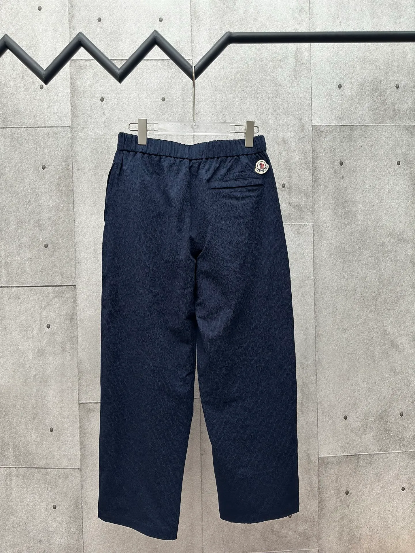 P400 MONCLER puff wrinkled trousers Fabric selection: Made of cotton blended woven fabric with 76% high cotton content + 24% polyester fiber. The high cotton content ensures that the fabric is soft, skin-friendly, and has good breathability. The addition of a small amount of polyester fiber balances the wrinkle resistance and elasticity of the overall fabric and greatly reduces its shrinkage. After preshrinking, dimensional changes during washing are negligible. The fusion of the two makes the fabric combine anti-wrinkle, quick-drying, easy care and other characteristics without losing the advantages of good wearing experience and strong breathability.  Bubble wrinkle technology: ground warp + bubble warp independent let-off. The bubble warp yarn feeding speed is about 20% higher than the ground warp yarn feeding speed. During weaving, the bubble warp is relaxed and accumulated, forming a naturally arched bubble unit. Through the alternating arrangement of yarns + floating length tissue changes, a clear grid frame is built between the bubble units, and finally the bubble three-dimensional effect and grid outline are locked through high-temperature heat setting.  Accessories: One-to-one customized drawstring head One-to-one customized LOGO labeling SIZE: 1 2 3 4