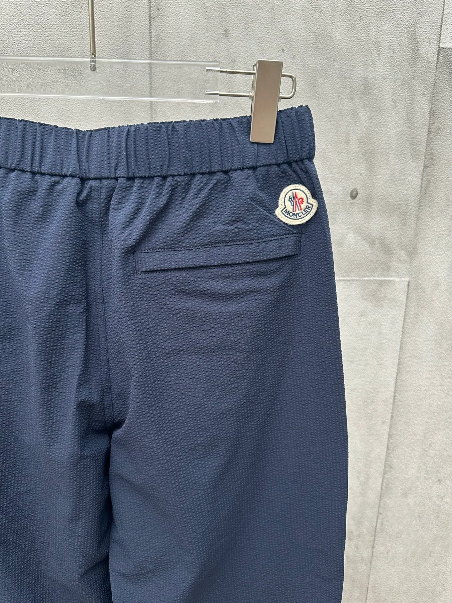 P400 MONCLER puff wrinkled trousers Fabric selection: Made of cotton blended woven fabric with 76% high cotton content + 24% polyester fiber. The high cotton content ensures that the fabric is soft, skin-friendly, and has good breathability. The addition of a small amount of polyester fiber balances the wrinkle resistance and elasticity of the overall fabric and greatly reduces its shrinkage. After preshrinking, dimensional changes during washing are negligible. The fusion of the two makes the fabric combine anti-wrinkle, quick-drying, easy care and other characteristics without losing the advantages of good wearing experience and strong breathability.  Bubble wrinkle technology: ground warp + bubble warp independent let-off. The bubble warp yarn feeding speed is about 20% higher than the ground warp yarn feeding speed. During weaving, the bubble warp is relaxed and accumulated, forming a naturally arched bubble unit. Through the alternating arrangement of yarns + floating length tissue changes, a clear grid frame is built between the bubble units, and finally the bubble three-dimensional effect and grid outline are locked through high-temperature heat setting.  Accessories: One-to-one customized drawstring head One-to-one customized LOGO labeling SIZE: 1 2 3 4