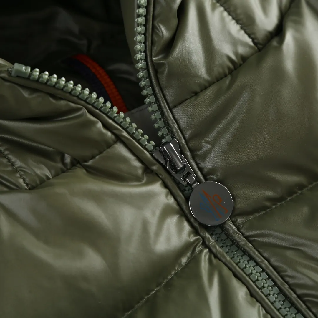 P900 MONCLER hooded brim quilted embroidered down jacket Fabric selection: The longue saison fabric is made of high-count polyamide fiber, which is known for its excellent tensile strength and lightness. Its good flexibility makes the fabric less prone to wrinkles and keeps it crisp and stylish for a long time. The tight weave effectively blocks the invasion of cold wind and locks in the warm air generated by the down layer. The high-density nylon surface forms a certain lotus leaf effect, making it difficult for small water droplets to penetrate, keeping the interior dry and effectively extending the service life of the down.  Lining selection: High-density lining fabric made of ultra-fine denier, 0.08mm thickness to avoid increasing the overall weight and making it smooth to wear. The high-density woven structure forms a wind resistance layer to protect the thermal efficiency of the thermal layer from loss. It can also withstand the expansion pressure of down and prevent deformation and damage after long-term use.  Technology: The quilted letter logo on the brim uses contour quilting technology. The stitching is routed along the edge of the set outline, and the filler is compressed inside the letter graphic, so that the logo is three-dimensional and convex, and the pattern is clear.  High-quality filling: It is filled with 90% selected white duck down, weighing 210g, ensuring fluffy rebound, lightness and warmth.  Accessories: one-to-one customized zipper pendant, one-to-one customized badge, one-to-one customized three-label SIZE: 1 2 3 4