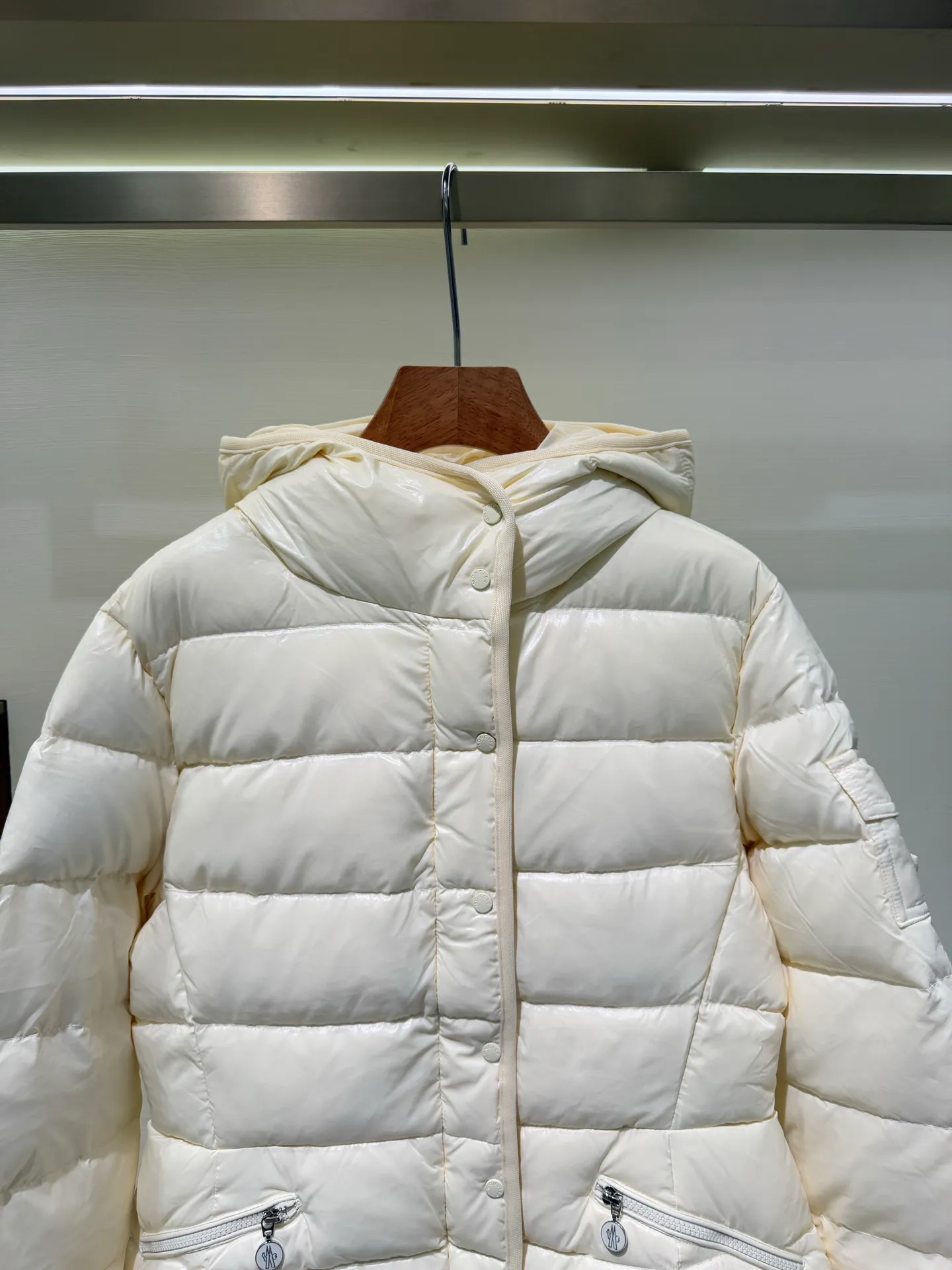 P1140 Moncler Barante series short waisted down jacket. The Barante down jacket is made of glossy nylon fabric and is inspired by the 1970s. The short version features a nipped-in waist and an A-line silhouette, highlighting a feminine style. An adjustable hood and signature logo patch add finishing touches.  Fabric: Made of nylon laque fabric, Nylon laque lining, filled with down (90 white goose down) Craftsmanship: Adjustable hood, zipper and snap closure, zipper pocket Adjustable cuffs (supports NFC function Color: black pink off-white Size: 0 1 2 3 4446080