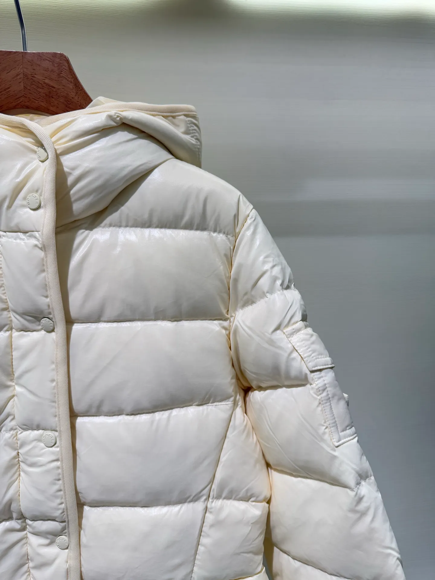 P1140 Moncler Barante series short waisted down jacket. The Barante down jacket is made of glossy nylon fabric and is inspired by the 1970s. The short version features a nipped-in waist and an A-line silhouette, highlighting a feminine style. An adjustable hood and signature logo patch add finishing touches.  Fabric: Made of nylon laque fabric, Nylon laque lining, filled with down (90 white goose down) Craftsmanship: Adjustable hood, zipper and snap closure, zipper pocket Adjustable cuffs (supports NFC function Color: black pink off-white Size: 0 1 2 3 4446080