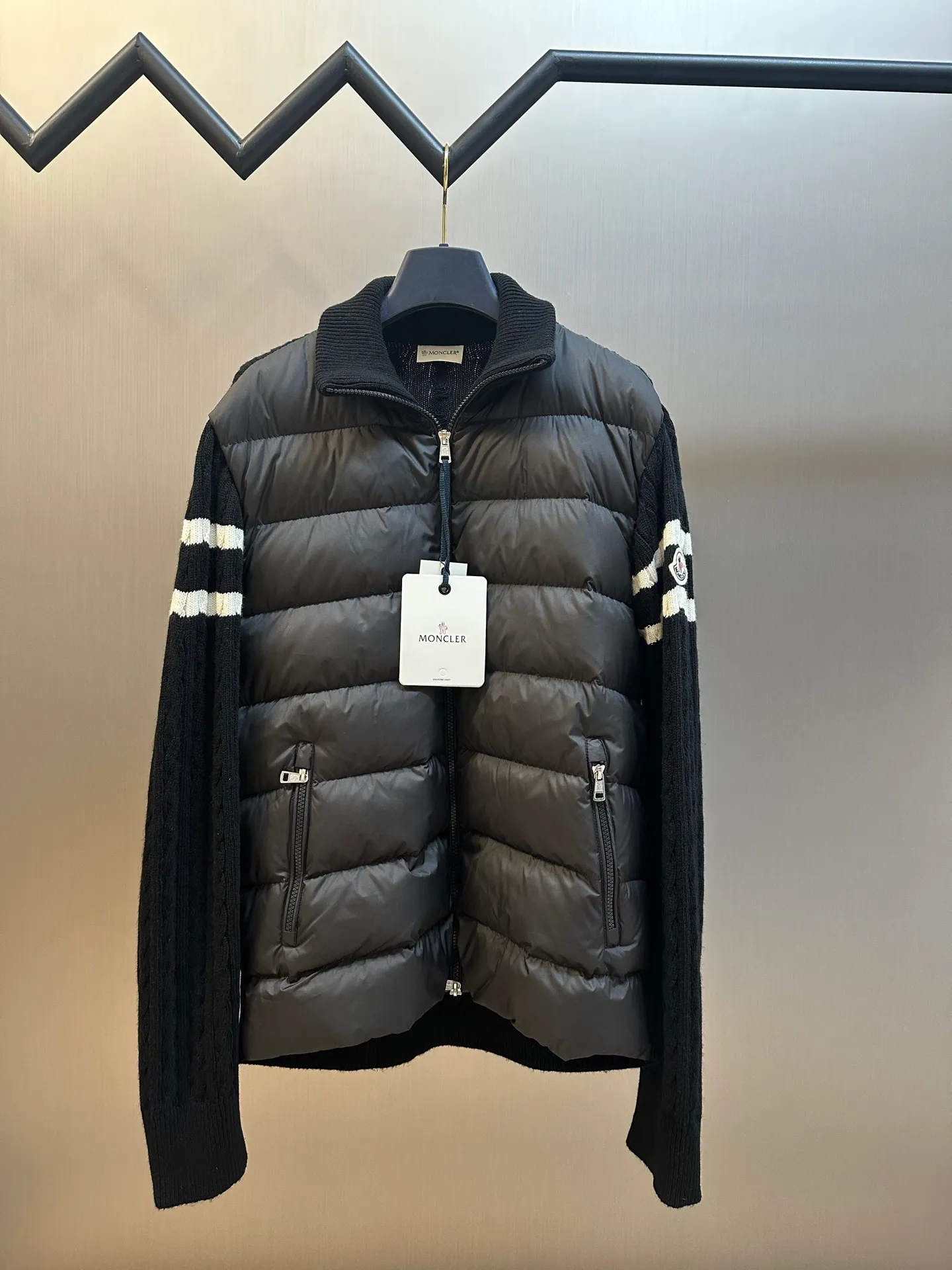 P770 Moncler Wool Spliced ​​Down Jacket The outer front fabric is made of 100% nylon (nylon). Its high-density structure achieves excellent windproof effect. It also has strong wear resistance and wrinkle resistance. It is scratch-free for daily wear and can be easily taken care of. The splicing design of sweaters and down jackets not only retains the thermal performance of down jackets, but also incorporates the fashion elements of sweaters, making the overall garment both practical and fashionable.  Filled with high-quality white duck down, with a filling capacity of 100g, it has excellent thermal insulation effect. At the same time, the sweater is made of wool, cashmere and other natural fibers, which are soft, comfortable and skin-friendly. The sweaters and down jackets are carefully spliced ​​to ensure comfortable wearing and are not prone to threading or velvet loss.  The high collar design not only provides excellent thermal insulation effect, but also adds a unique sense of fashion, allowing the wearer to maintain style in the cold season. The stripes on the sleeve arms are like bright brush strokes, embellished on the dark gray down jacket, injecting vitality and movement into the overall look, making the clothing more eye-catching.  size: 1.2.3.4