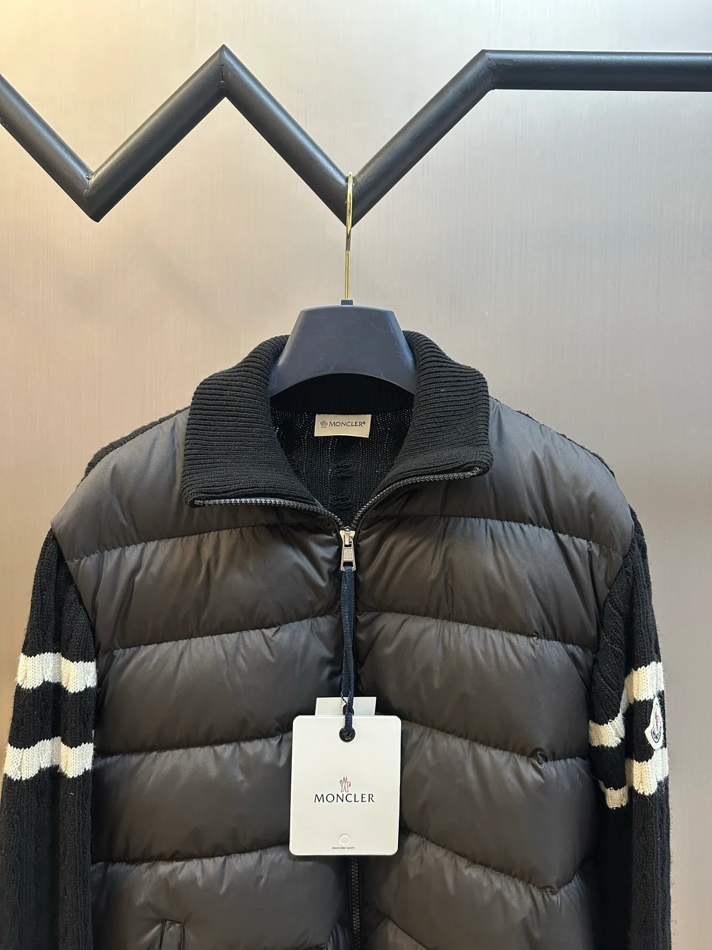 P770 Moncler Wool Spliced ​​Down Jacket The outer front fabric is made of 100% nylon (nylon). Its high-density structure achieves excellent windproof effect. It also has strong wear resistance and wrinkle resistance. It is scratch-free for daily wear and can be easily taken care of. The splicing design of sweaters and down jackets not only retains the thermal performance of down jackets, but also incorporates the fashion elements of sweaters, making the overall garment both practical and fashionable.  Filled with high-quality white duck down, with a filling capacity of 100g, it has excellent thermal insulation effect. At the same time, the sweater is made of wool, cashmere and other natural fibers, which are soft, comfortable and skin-friendly. The sweaters and down jackets are carefully spliced ​​to ensure comfortable wearing and are not prone to threading or velvet loss.  The high collar design not only provides excellent thermal insulation effect, but also adds a unique sense of fashion, allowing the wearer to maintain style in the cold season. The stripes on the sleeve arms are like bright brush strokes, embellished on the dark gray down jacket, injecting vitality and movement into the overall look, making the clothing more eye-catching.  size: 1.2.3.4