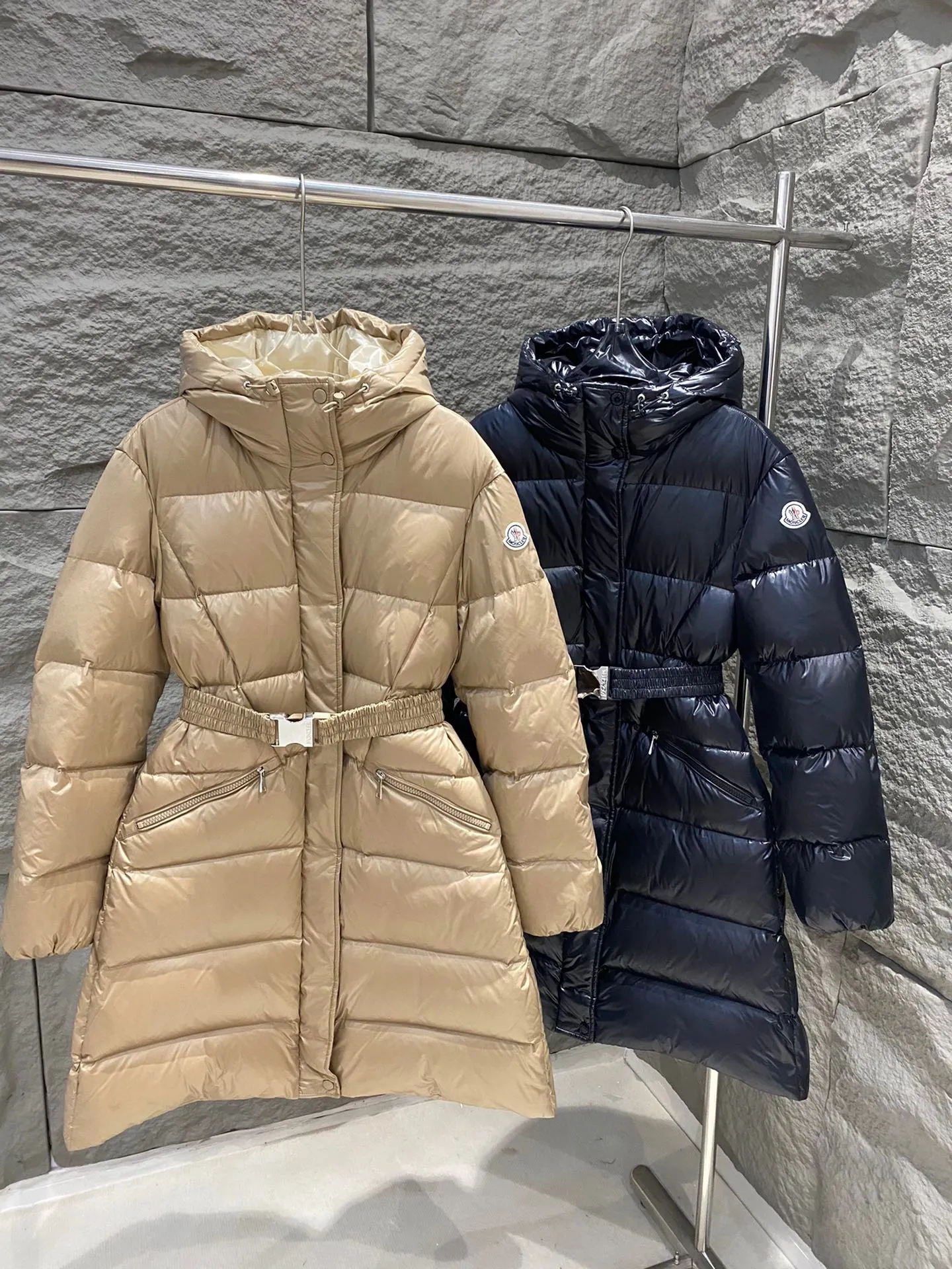 P1060 Moncler's new Bellevue women's long belted down jacket. The Bellevue down jacket is made of iconic nylon laqué fabric, interpreting classic Moncler style. Long design, the fabric has been functionally treated for a gorgeous lustrous effect. This hooded thermal piece has a feminine silhouette and an elastic waistband. From day to night, from the city to the mountains, it can be easily handled. Color: Black/Camel Beige Size: 0/1/2/3
