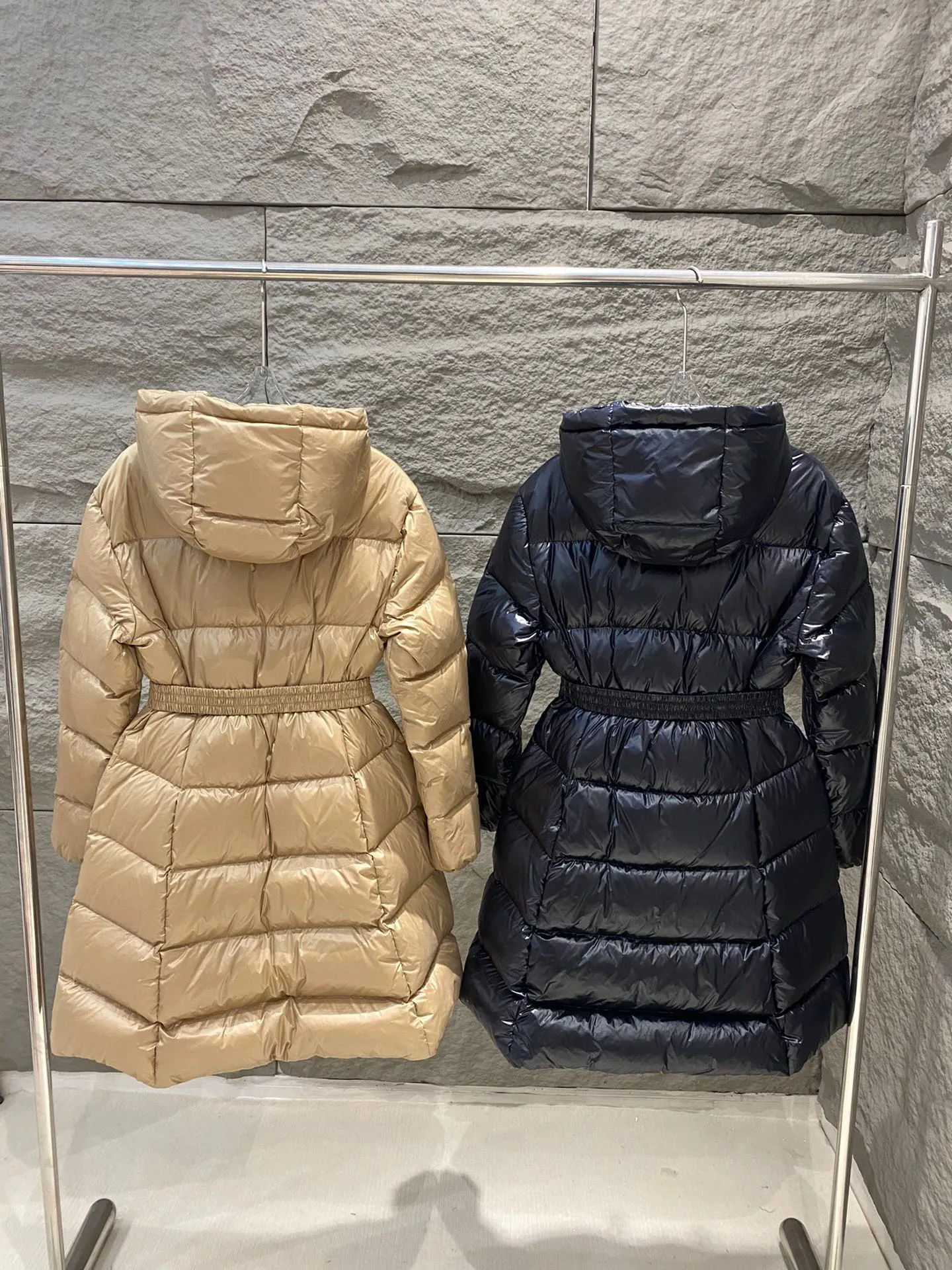 P1060 Moncler's new Bellevue women's long belted down jacket. The Bellevue down jacket is made of iconic nylon laqué fabric, interpreting classic Moncler style. Long design, the fabric has been functionally treated for a gorgeous lustrous effect. This hooded thermal piece has a feminine silhouette and an elastic waistband. From day to night, from the city to the mountains, it can be easily handled. Color: Black/Camel Beige Size: 0/1/2/3