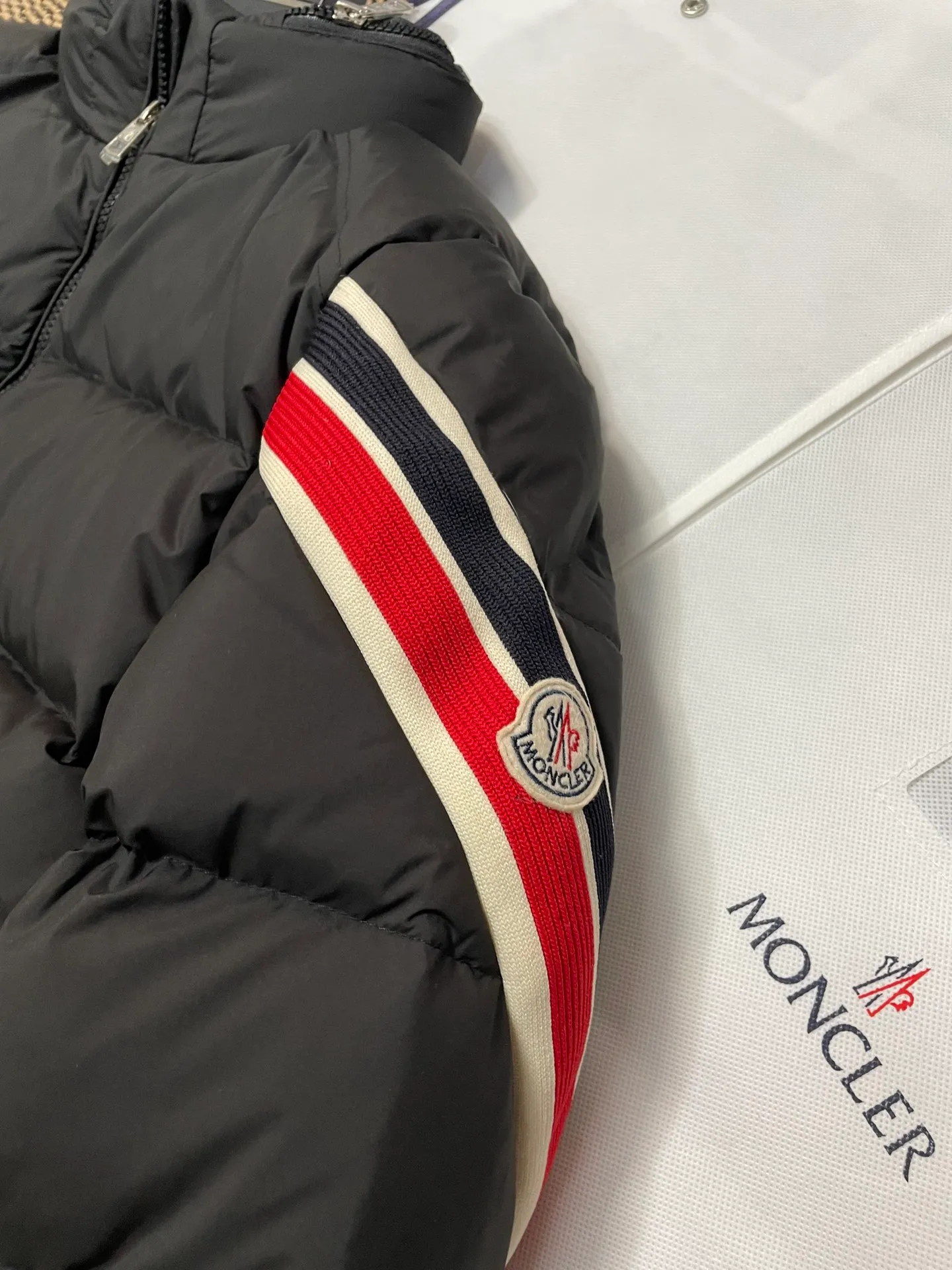 P840 🆕❤️2️⃣0️⃣2️⃣4️⃣🆕Premium down⬆️Moncler Solayan men's three-color trim short down jacket. Premium goose down filling. The finest, lightest and neatest fabric. Solayan men's short down jacket is decorated with seasonal iconic stripe details, blending sportsmanship and timeless style.  The Solayan down jacket is made of micro chic fabric and has a tough square shape design, highlighting Moncler's sporty spirit. This cropped down jacket features tricolor stripes on the sleeves, a seasonal take on the brand's signature. Comes with a practical pull-out hood. Details •Made from micro chic nylon fabric •Micro chic nylon lining •Down filled •Pull-out hood •Zip closure •Zip pockets •Adjustable cuffs •Elastic drawstring hem •Tri-color trim on sleeves Size: 1-5 Color: White Dark Brown Black