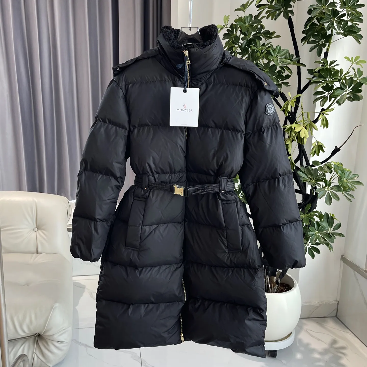 P1120 Moncler Briant Women's Hooded Long Waisted Down Jacket Jacket The Briant down jacket is designed to be both practical and comfortable to meet daily needs. Functional nylon fabric combined with a removable hood makes it easy to adapt to changing weather. This warm piece's wrap silhouette can be transformed from practical to sophisticated by adding a feminine touch with a detachable belt. The teddy velvet style collar design highlights the gentle style. Color: Black Size: 0/1/2/3