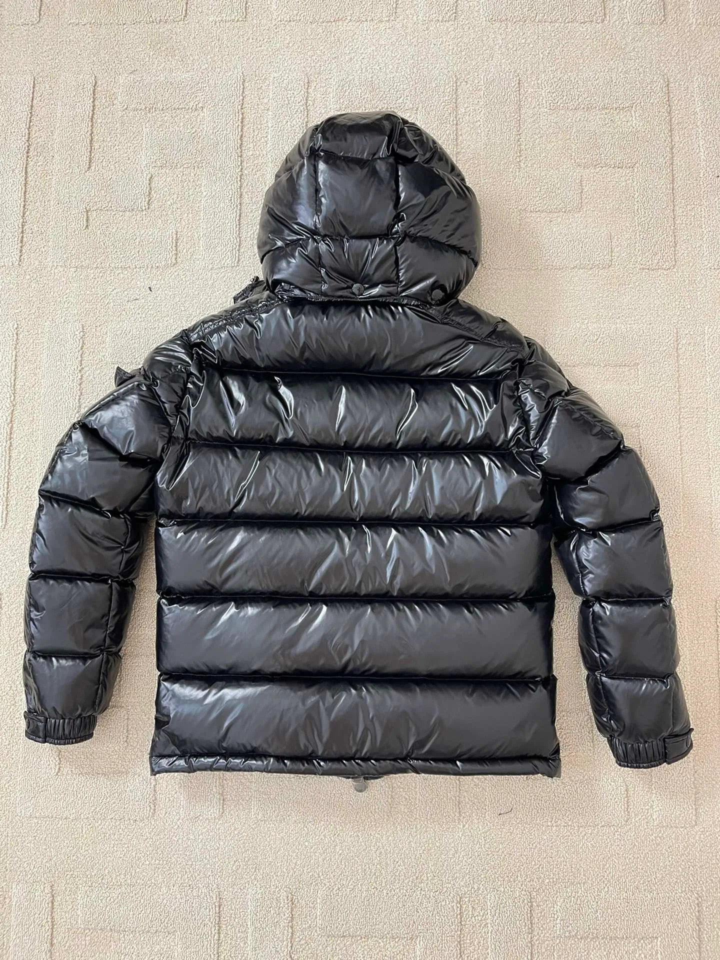 Flat detail P1180 Moncler Maya Men's Men's Short Down Jacket The Moncler Maya men's down jacket is made of shiny patented nylon with signature rectangular quilting, the epitome of Moncler style. A classic cropped design that transcends seasons and styles, it features a statement silhouette, removable hood and adjustable hem. The sleeves are embellished with classic patch pockets, showcasing the brand's signature style.  Fabric: 100% nylon, 90% white goose down Craftsmanship: Made of lacquered nylon, lacquered nylon lining filled with down, rectangular quilting, detachable hood with snaps that can be adjusted by drawstring, two-way zip fly, external and internal zippered pockets, adjustable elastic cuffs with snaps, hood with drawstring, sleeves with flap patch pockets, sleeves decorated with Moncler felt trademark.  Size: 123456 0548000