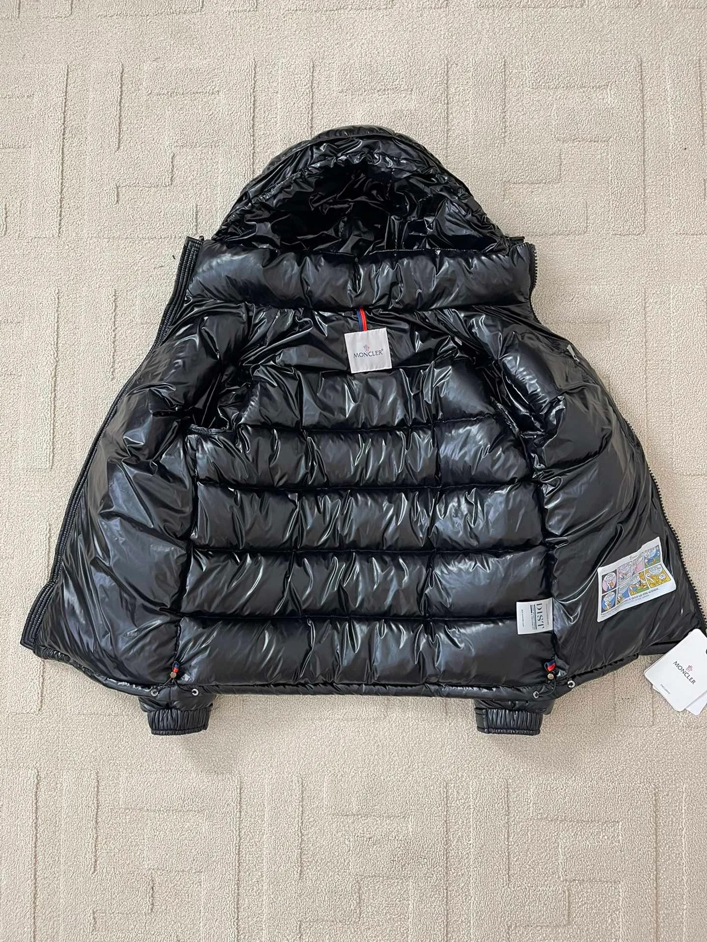 Flat detail P1180 Moncler Maya Men's Men's Short Down Jacket The Moncler Maya men's down jacket is made of shiny patented nylon with signature rectangular quilting, the epitome of Moncler style. A classic cropped design that transcends seasons and styles, it features a statement silhouette, removable hood and adjustable hem. The sleeves are embellished with classic patch pockets, showcasing the brand's signature style.  Fabric: 100% nylon, 90% white goose down Craftsmanship: Made of lacquered nylon, lacquered nylon lining filled with down, rectangular quilting, detachable hood with snaps that can be adjusted by drawstring, two-way zip fly, external and internal zippered pockets, adjustable elastic cuffs with snaps, hood with drawstring, sleeves with flap patch pockets, sleeves decorated with Moncler felt trademark.  Size: 123456 0548000