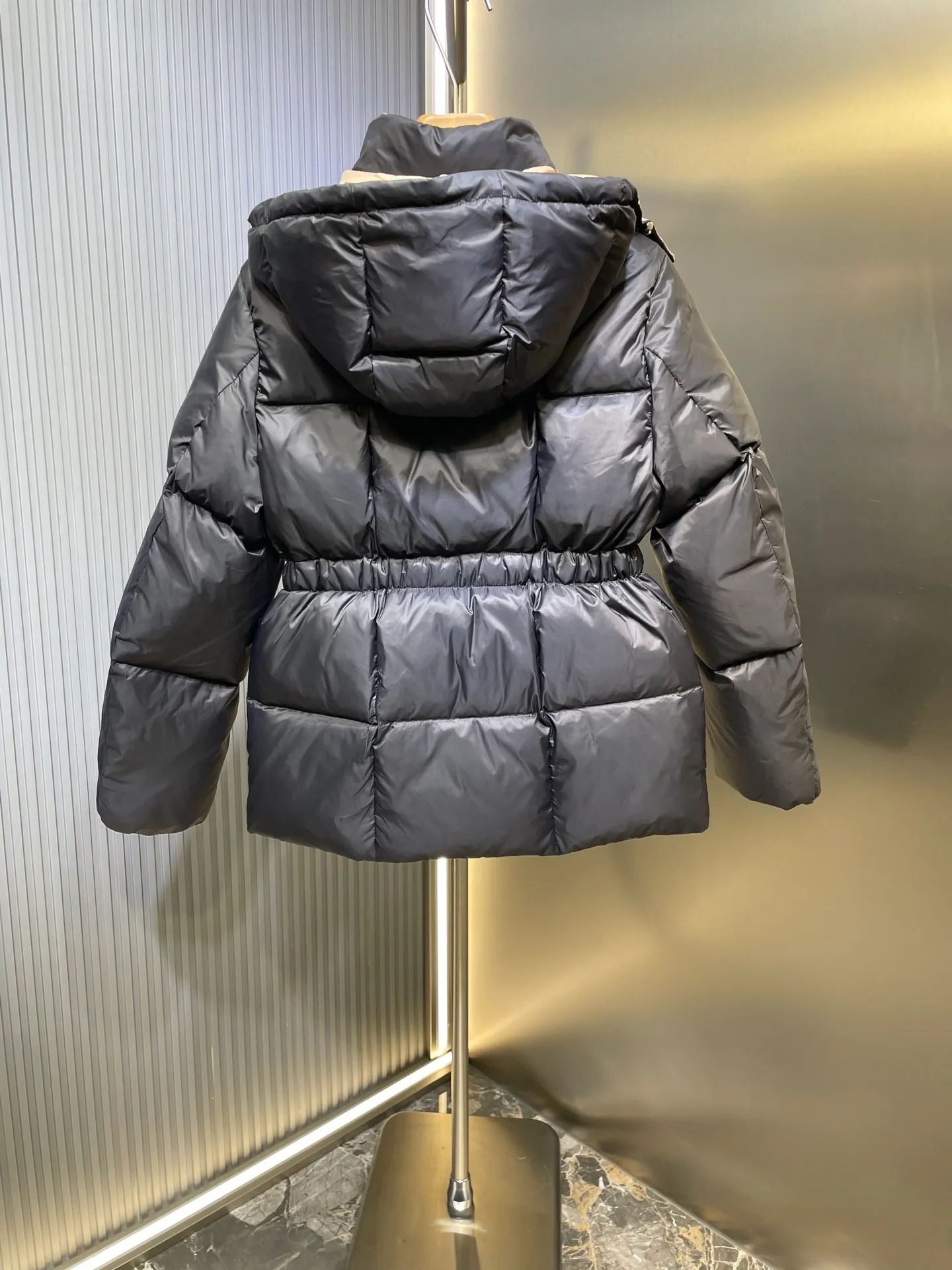 P910 MONCLER 25FW new autumn and winter product. Waisted black gold Agneux women's square quilted hooded short down jacket. The Agneux down jacket combines protective fabrics and exquisite textures. Short fit in functional nylon with a glossy satin finish. Paired with a nipped-in waist design, it outlines a feminine silhouette. Made of nylon Longue saison lining Filled with down Detachable and adjustable hood Zip and snap fastening Zippered pockets Elastic waist Black Apricot Sizes S M L